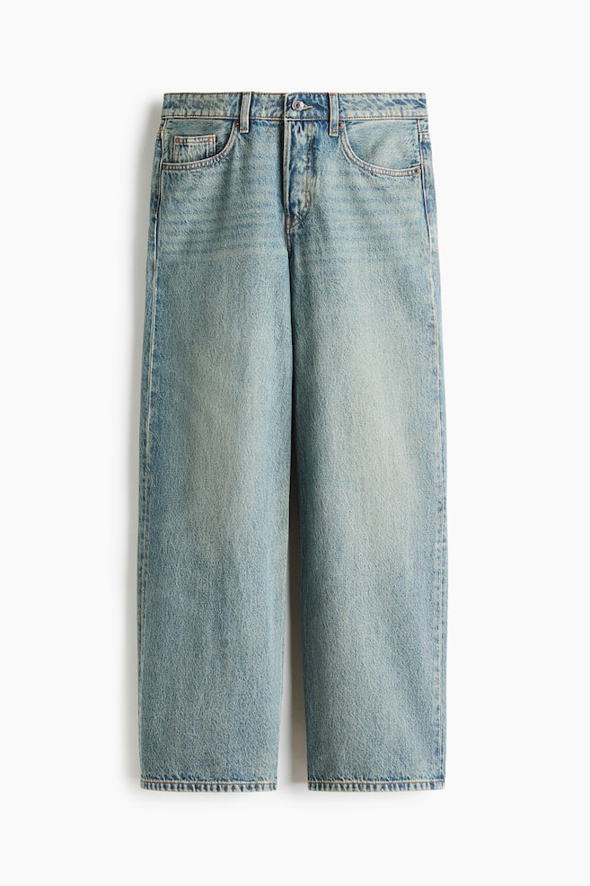 A pair of light-wash blue denim jeans is shown from the front, displaying a relaxed, wide-leg silhouette. The jeans feature classic five-pocket styling, belt loops, a metal button closure, and subtle fading along the thighs. - 1