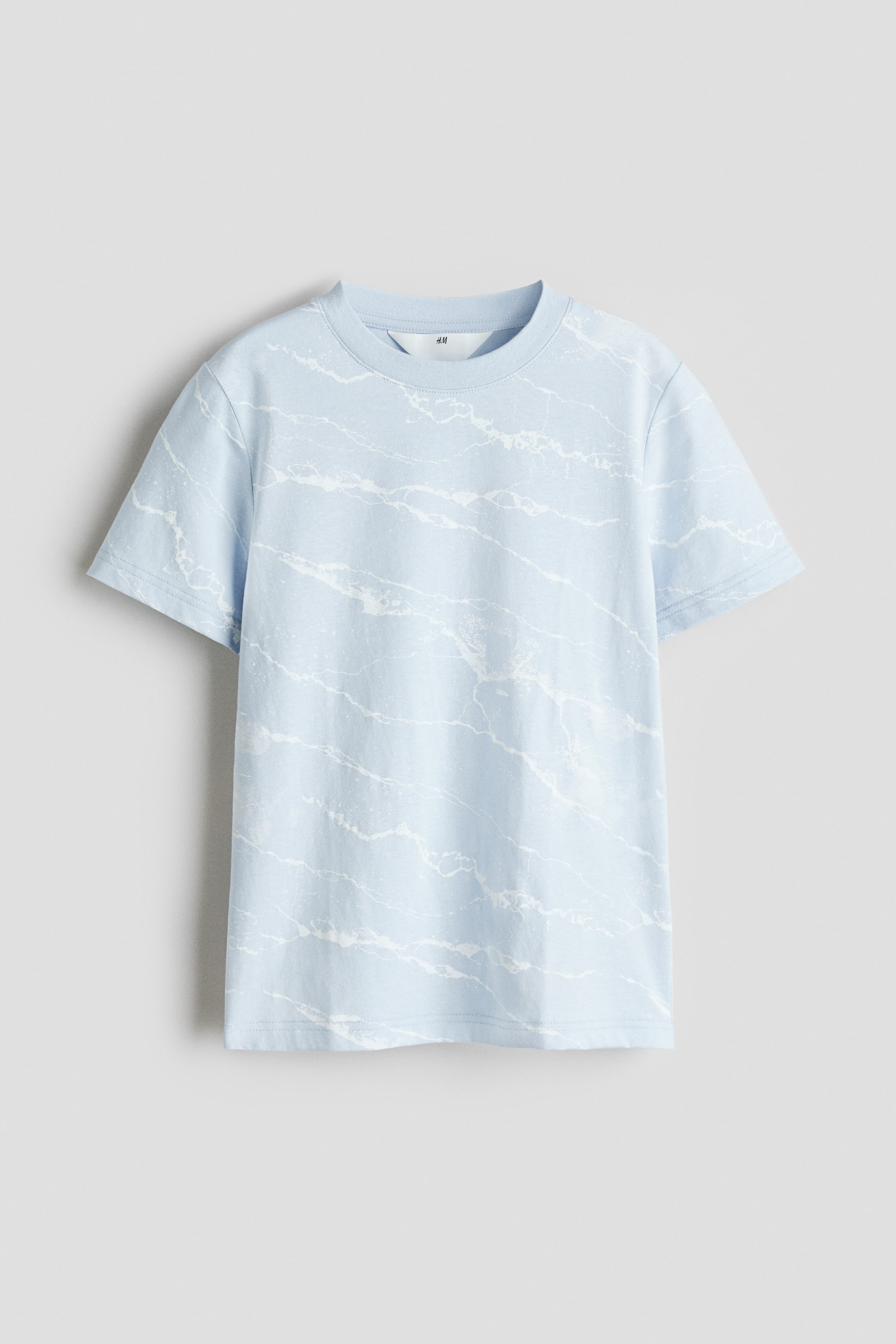 View larger image: The t-shirt showcases its front view, crafted from light blue printed cotton jersey. It features an all-over white marble-like pattern, a ribbed round neckline, and short sleeves.
