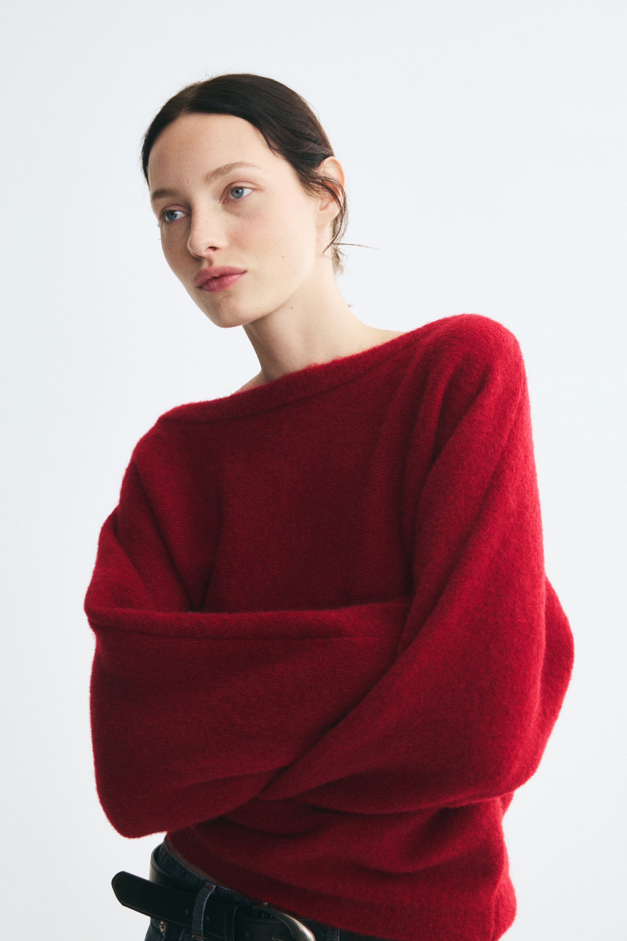 View larger image: The model is wearing a red brushed-knit sweater with a rib-trimmed boat neck and crossed arms. The sweater features a soft, textured finish and long, relaxed sleeves.