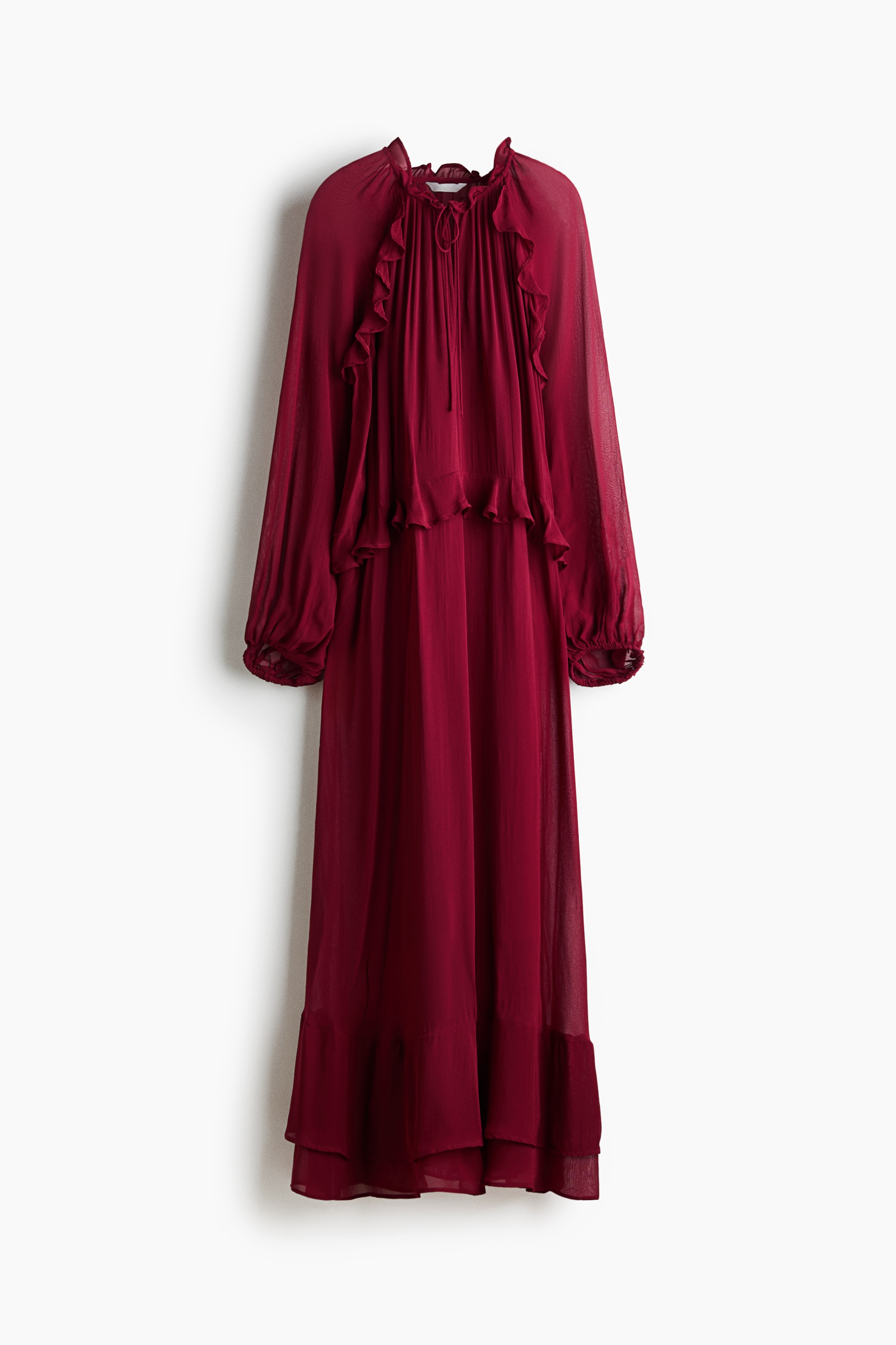 A front-facing view displays a dark red maxi dress crafted from a semi-sheer fabric, featuring a deep V-neckline with thin ties and ruffled flounce details along the shoulders and waist. The dress is styled with long balloon sleeves and a gently flared skirt that showcases tiered ruffles at the hem.
