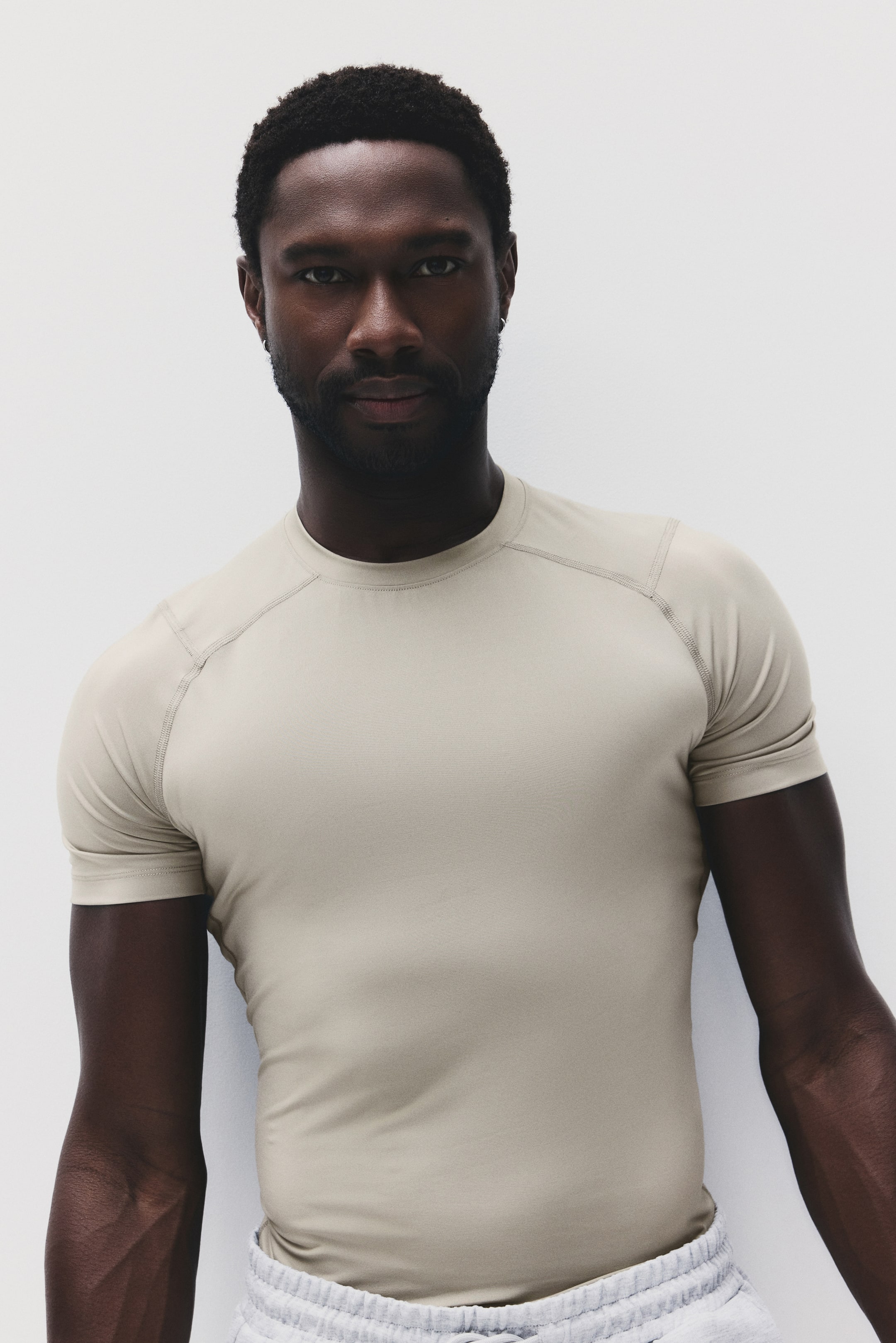 View larger image: A light beige short-sleeve t-shirt featuring a crew neck and raglan sleeves with visible topstitching. It offers a slim fit on the torso.