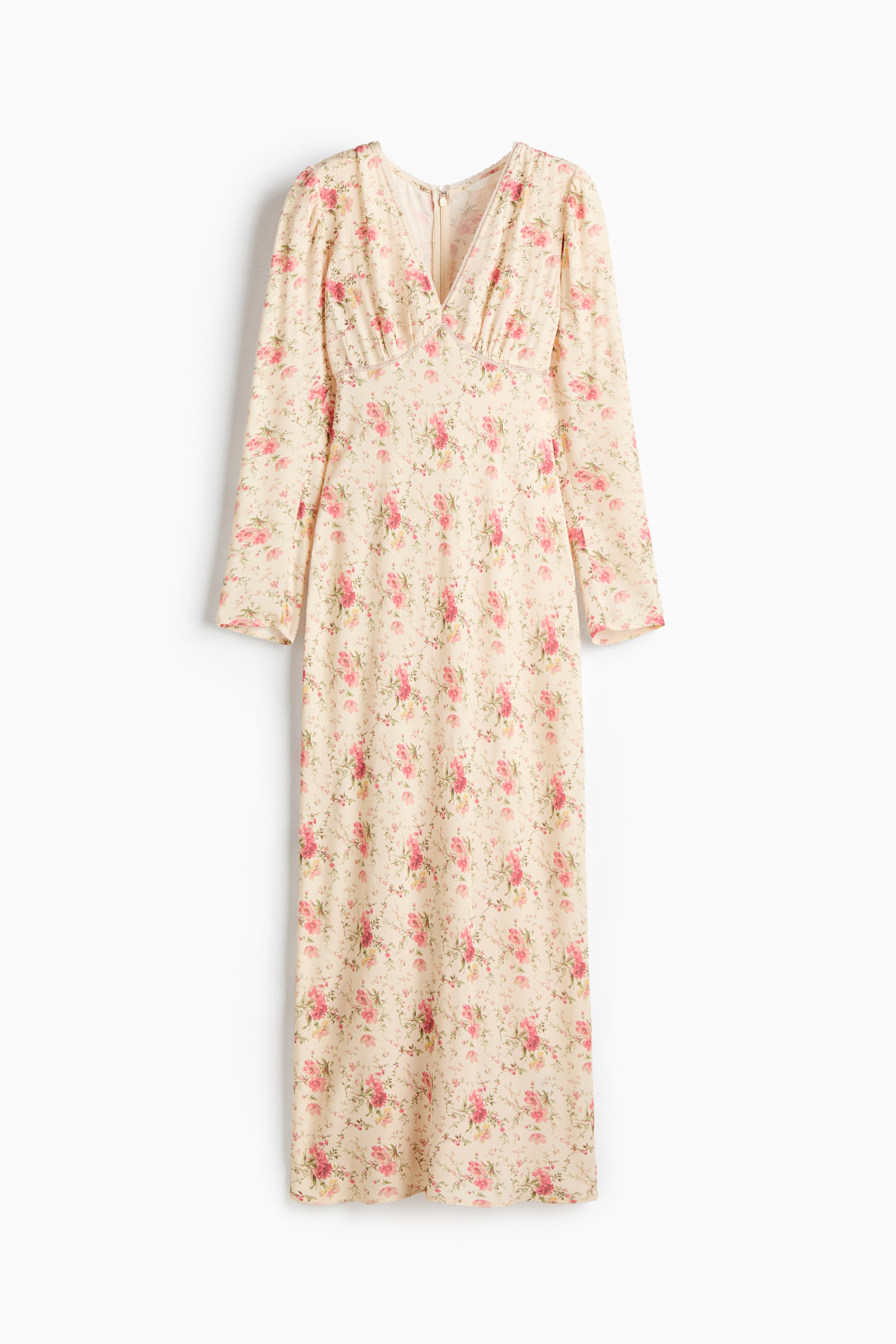 View larger image: The dress is presenting FRONT, featuring a cream base with a scattered pink and green floral print. It is designed with a V-neckline, long sleeves, and a gathered detail under the bust, flowing into a long skirt.