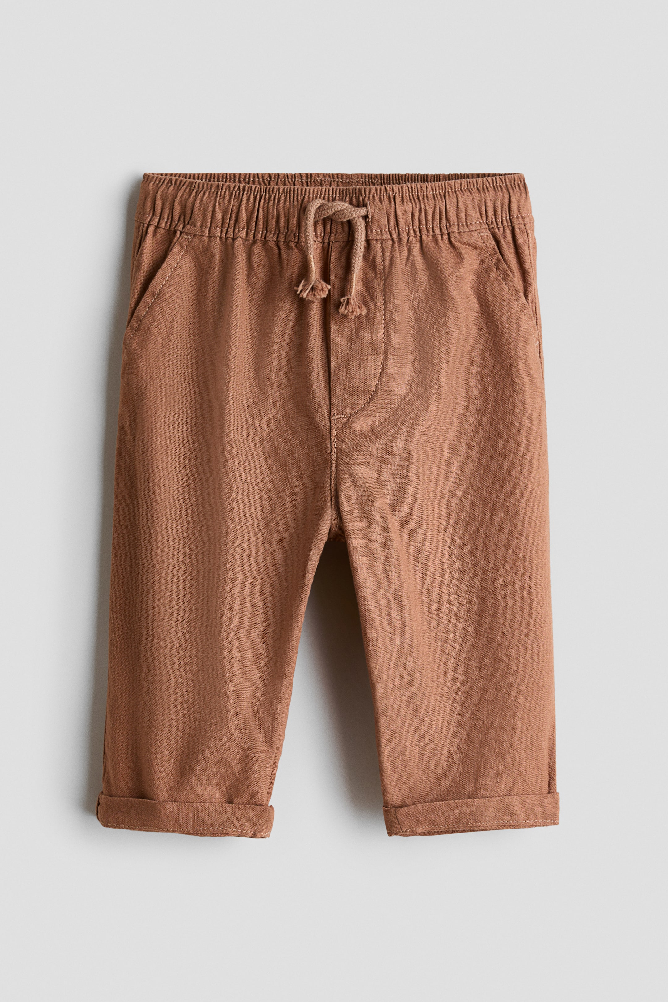 Voir une image plus grande: Pantalon brun, confectionné dans un mélange de coton et lin à tissage doux, présenté de face, affiche une taille élastiquée avec cordon de serrage noué, des poches latérales décoratives, une fausse braguette et des ourlets à revers.