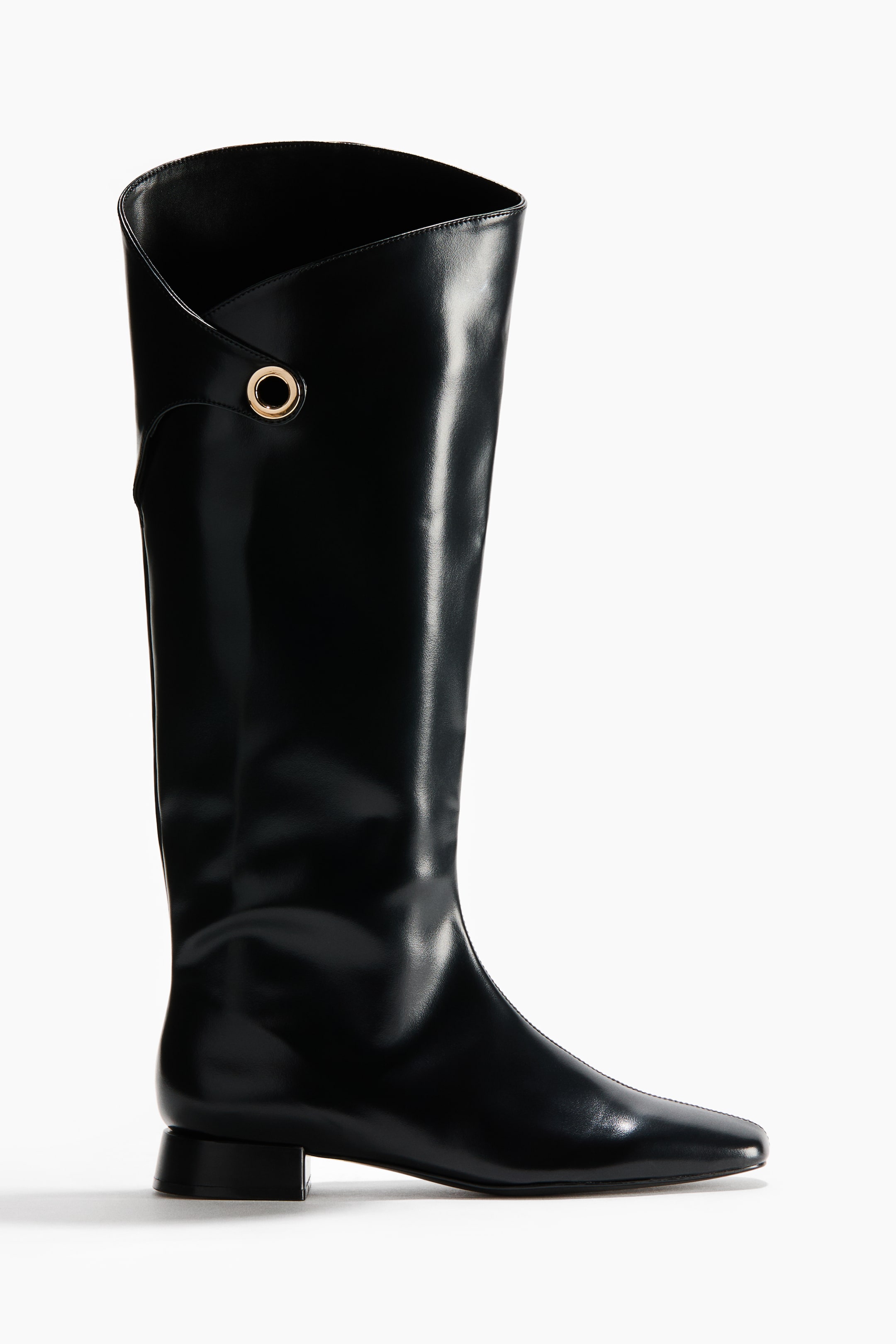 View larger image: A black tall boot features a glossy finish, a folded asymmetrical shaft with a single gold-toned eyelet, a pointed square toe, and a low block heel.