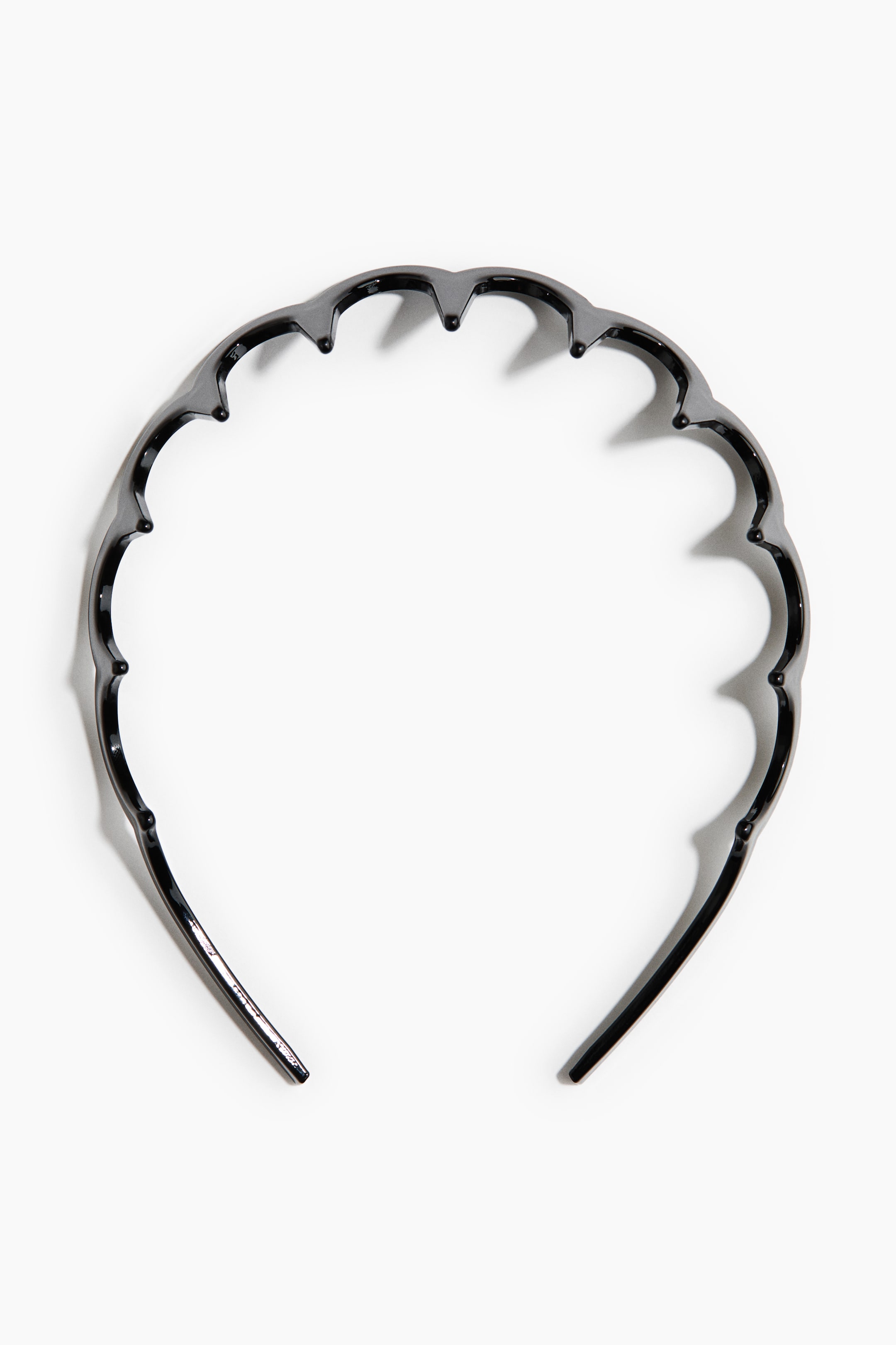 Ver imagen más grande: Una diadema de plástico negro presenta un borde superior festoneado con pequeños dientes redondeados.