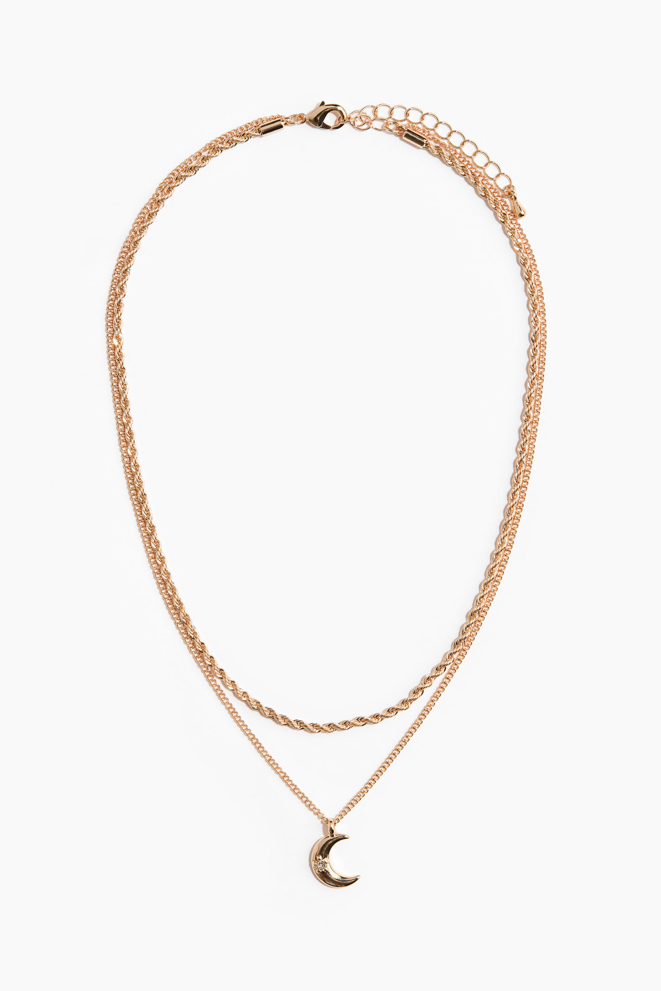 View larger image: A gold-toned metal layered necklace is shown from the front, featuring a shorter twisted rope chain layered above a longer, fine-link chain. The longer chain holds a polished crescent moon-shaped pendant embellished with a small inset rhinestone, with both chains connecting at a lobster clasp and adjustable extender chain.