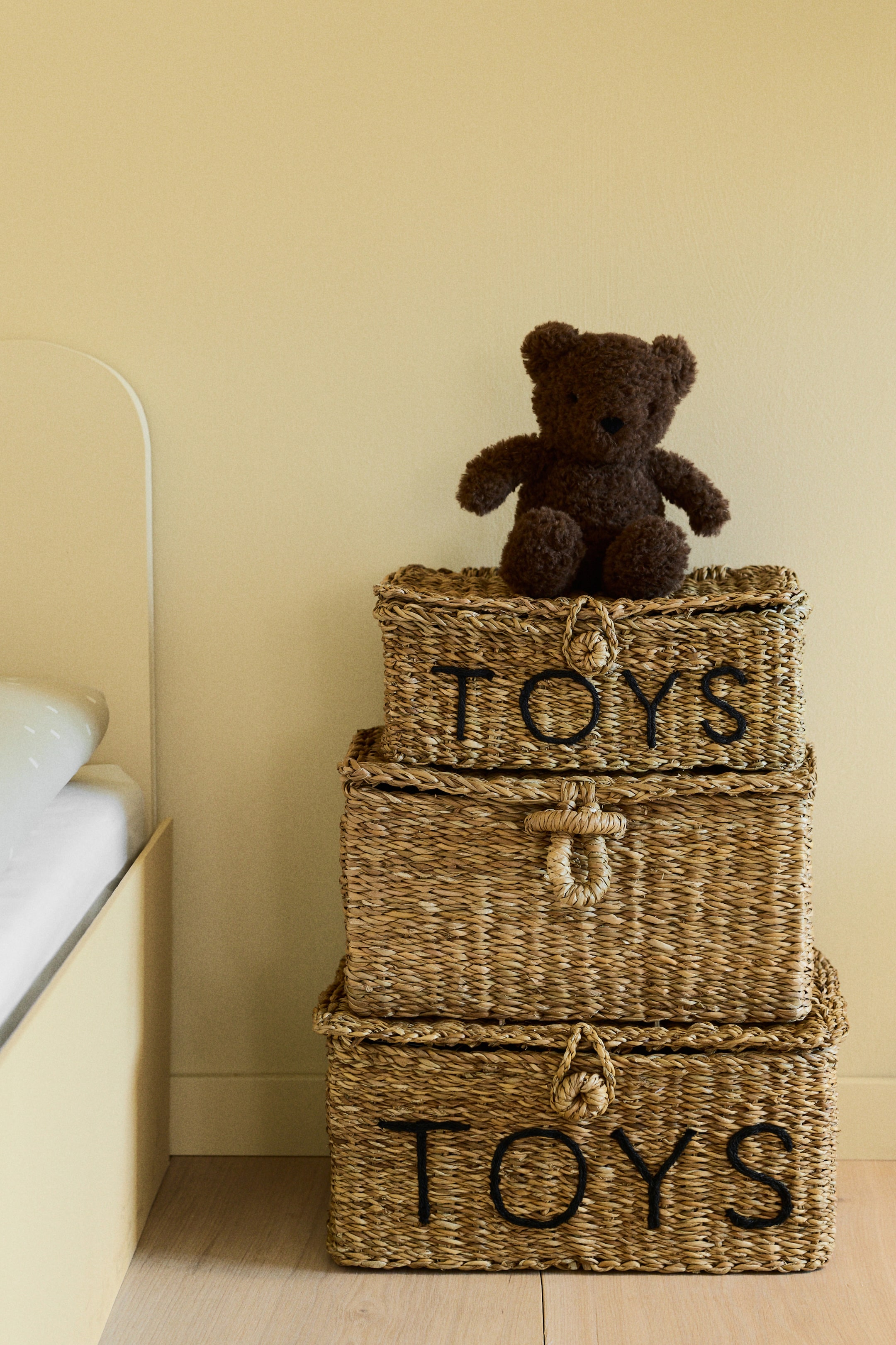 View larger image: A rectangular storage box is presenting its front, constructed from braided seagrass. It features an attached lid with a loop fastener and knob, and the word 'TOYS' is embroidered on its front.