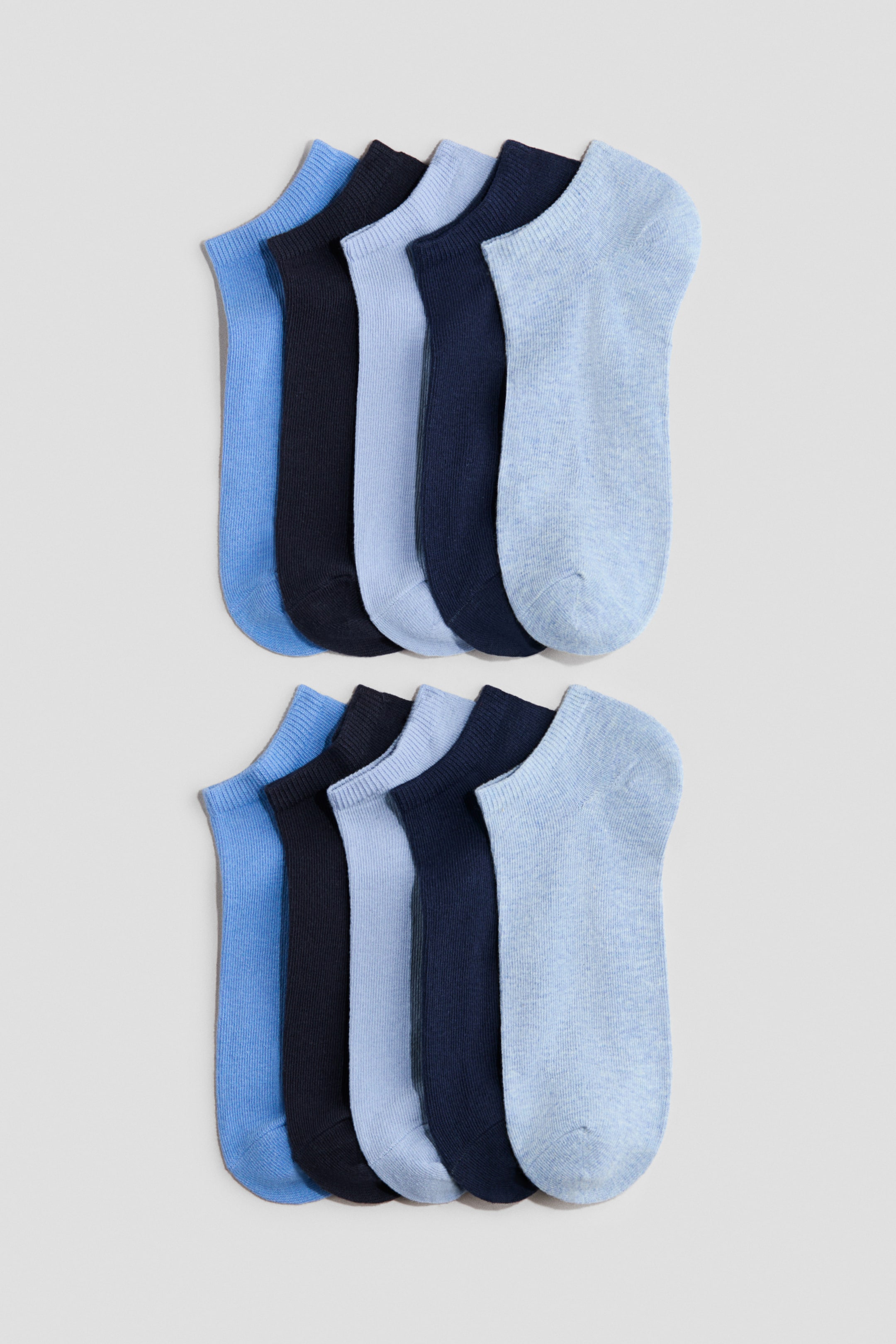 Ver imagen más grande: Diez calcetines tobilleros están dispuestos en dos filas horizontales, cada fila mostrando cinco calcetines superpuestos. Los calcetines se presentan en tonos alternos de azul claro, azul medio y azul marino, con puños acanalados en la abertura.