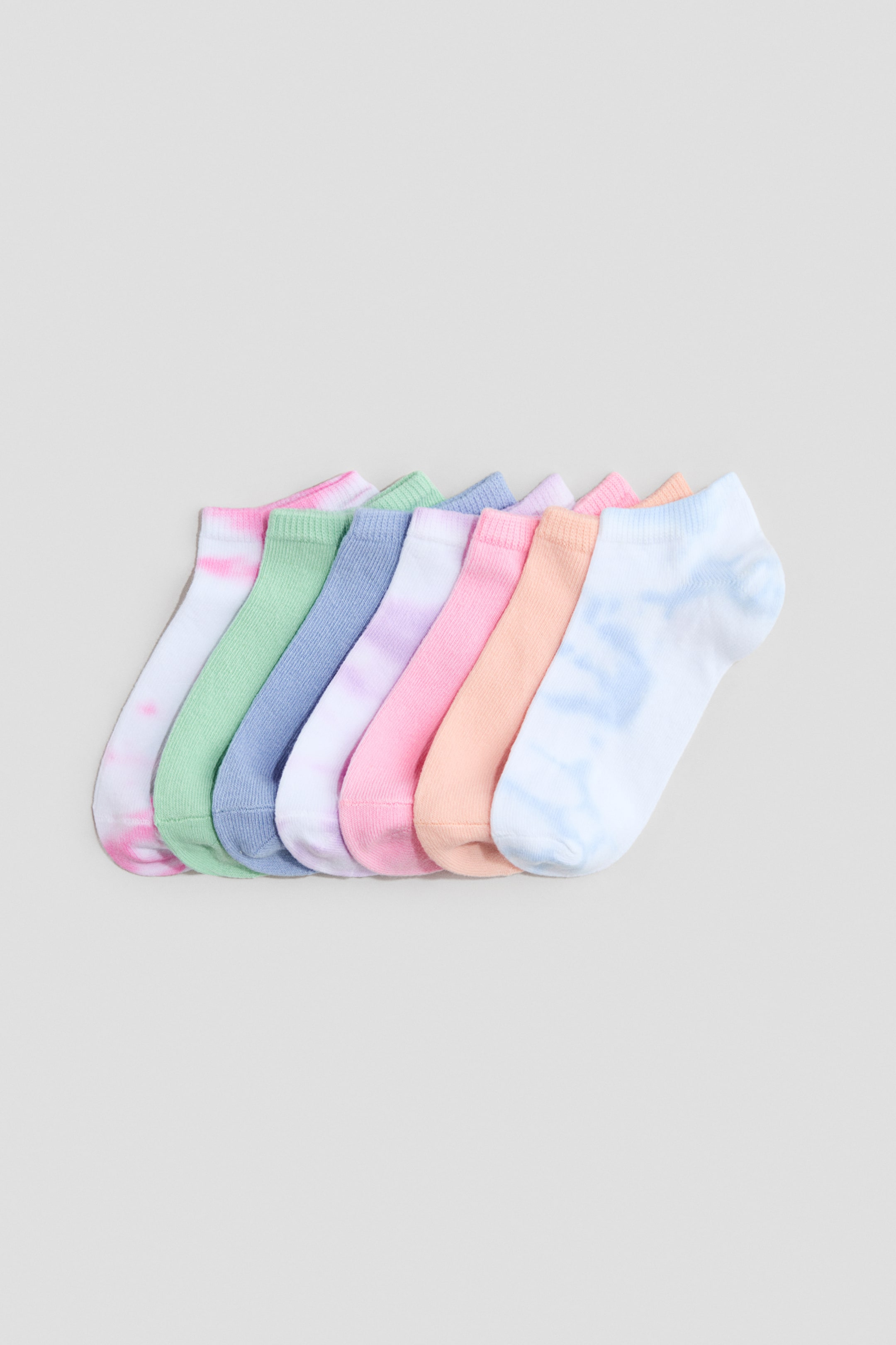 Visa större bild: Finknitna träningsstrumpor ligger i rad, med elastisk kant runt toppen. De visar upp en mängd pastellfärger, några med solida designer och andra med subtila tie-dye-mönster.
