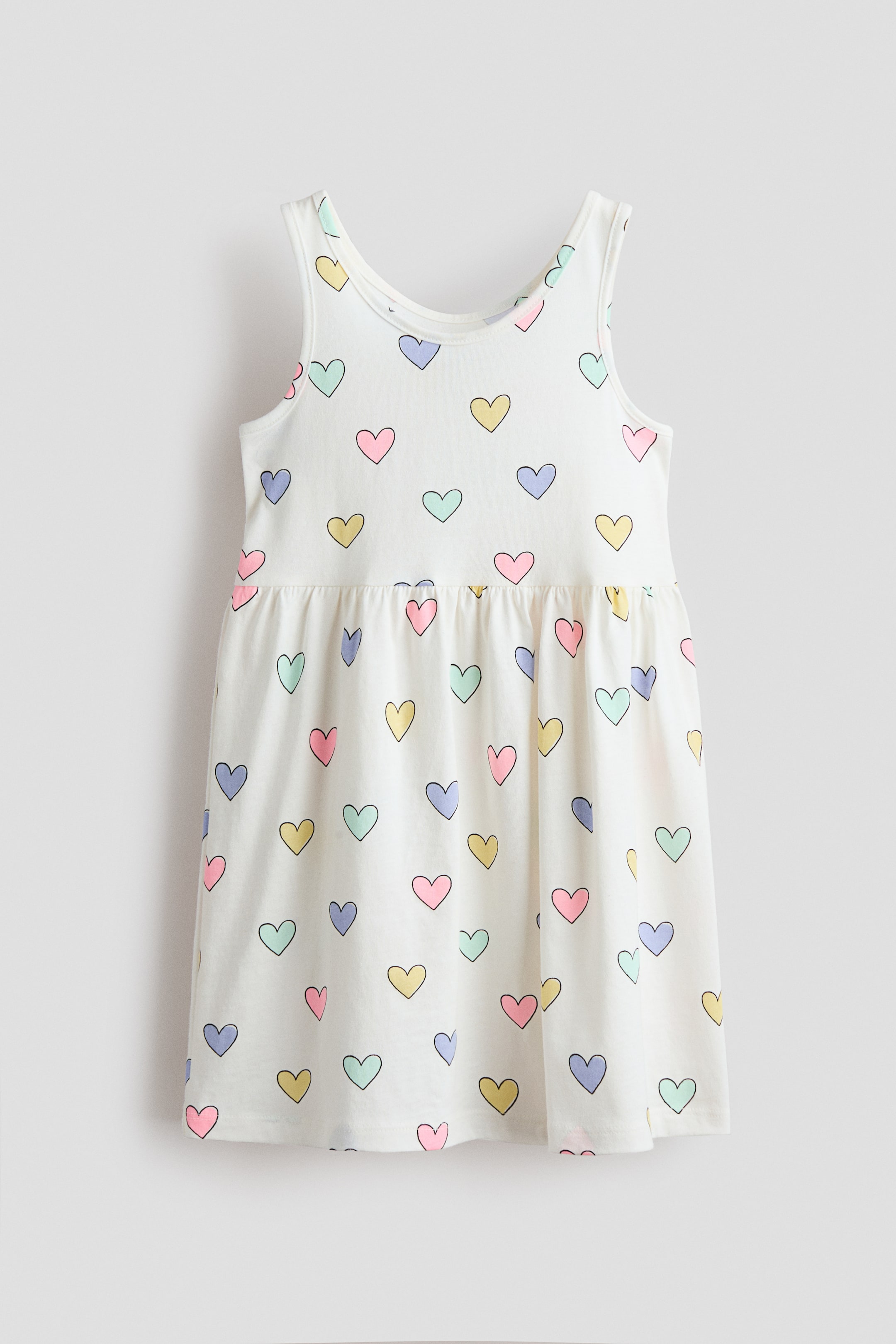 View larger image: The comfortable sleeveless dress in soft, patterned cotton jersey features a gathered seam at the waist and a gently flared skirt. Its FRONT is covered in a pattern of small, multicolored heart outlines, and it is designed with a scoop neckline and wide shoulder straps.