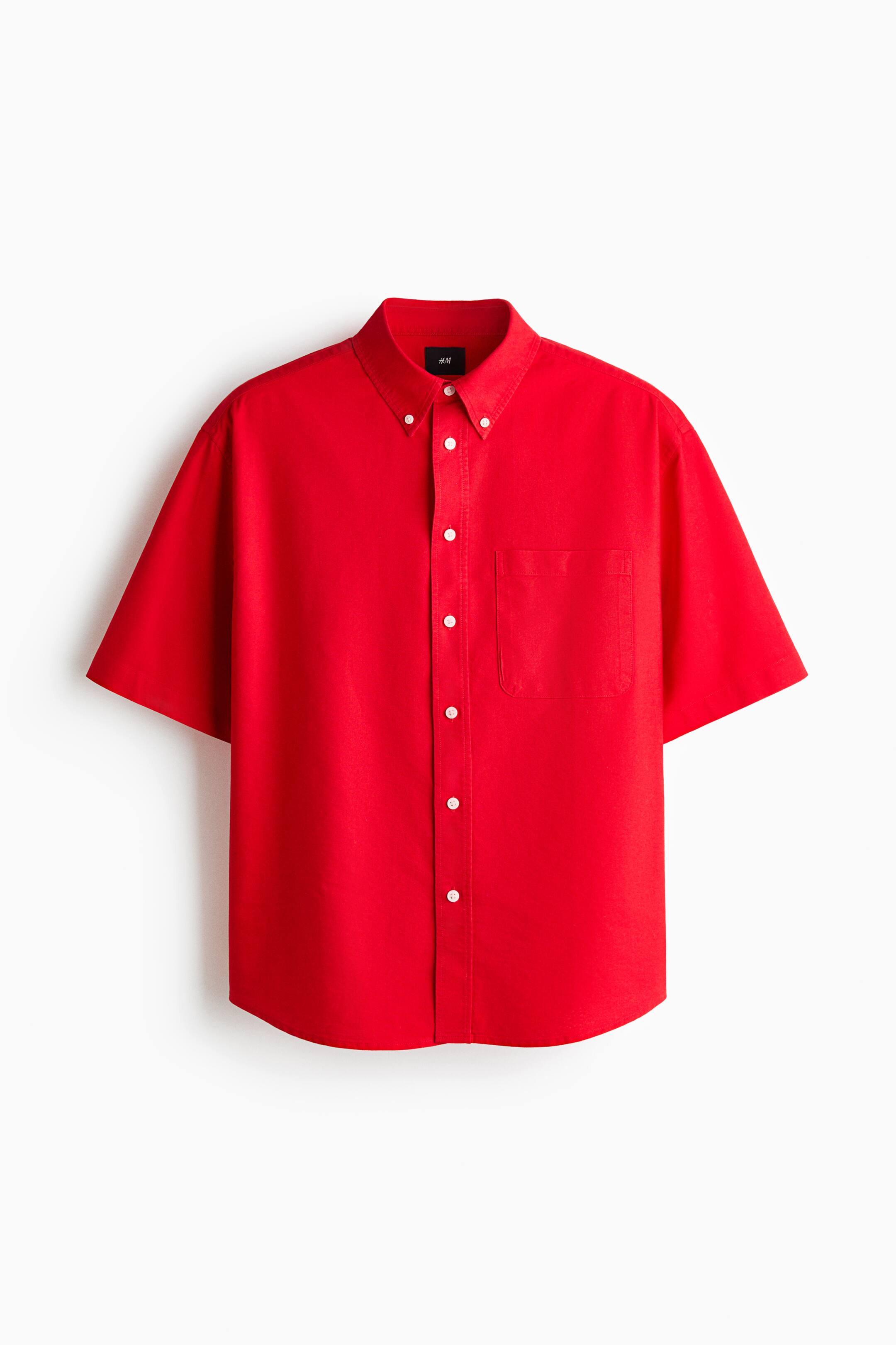 View larger image: Presenting a red Oxford cotton shirt with a button-down collar, featuring a classic front adorned with white buttons and short sleeves. It includes an open chest pocket on the left side and a subtly rounded hem, offering a relaxed fit from the front.