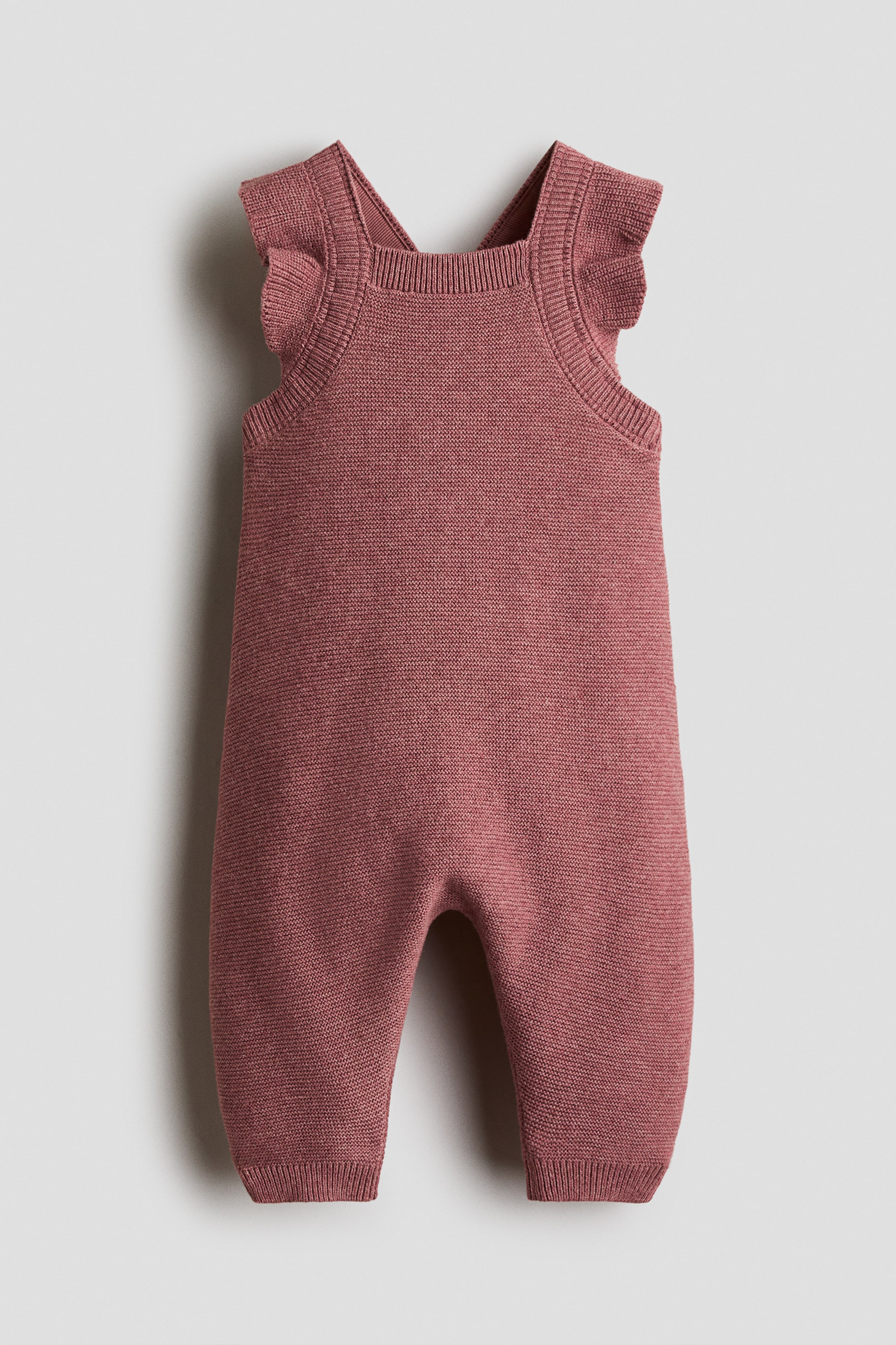 Visualizza immagine più grande: Un tutina in maglia rosa cipria per neonati presenta una texture a maglia fine, dettagli arricciati sulle spalle, uno scollo quadrato a coste e polsini gamba a coste.