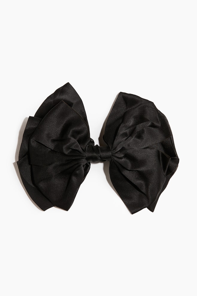 Un grand nÅud en satin noir est orienté vers lâavant, présentant des boucles volumineuses à plusieurs couches, rassemblées au centre par une bande de tissu nouée. - 1