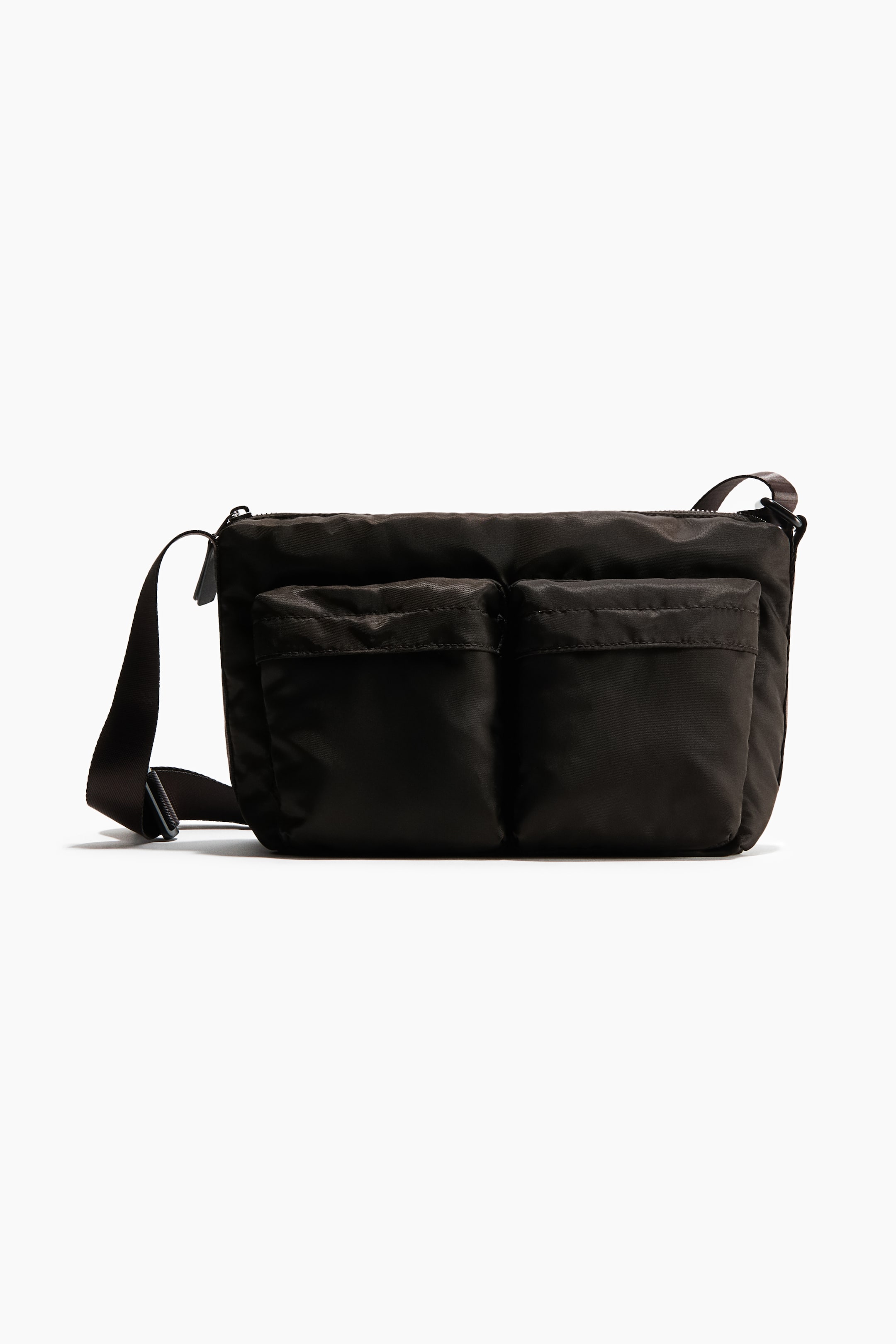 View larger image: A padded crossbody bag in dark brown woven fabric is shown from the front, featuring two outer front compartments with flap closures. The bag is designed with a top zip closure and an adjustable webbing shoulder strap with a slide buckle extending from the sides.