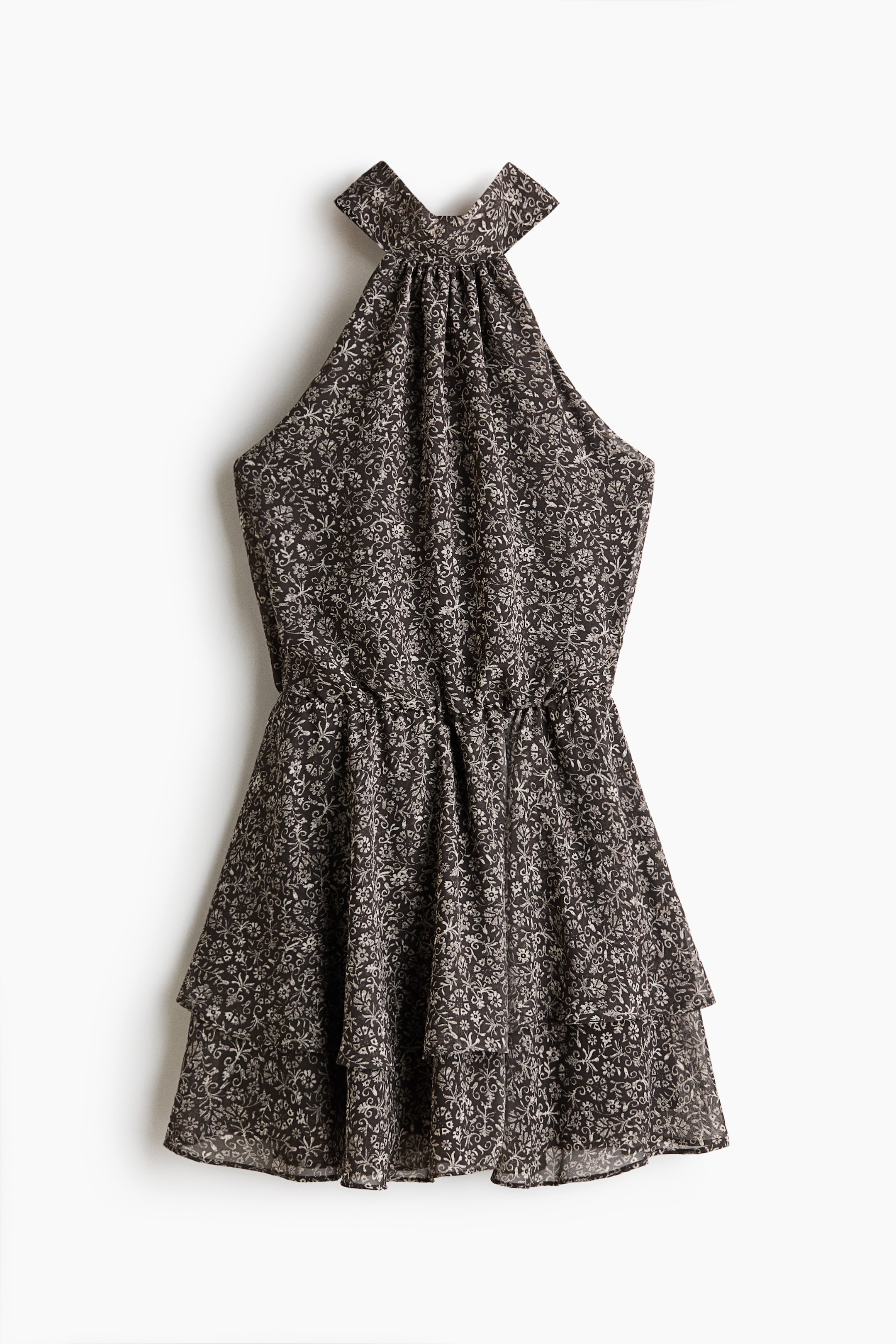 Ampliar la imagen: Una vista frontal del vestido muestra una tela oscura con un patrón floral claro e intrincado. Está diseñado con un escote halter fruncido, cintura elástica y una falda corta en capas.