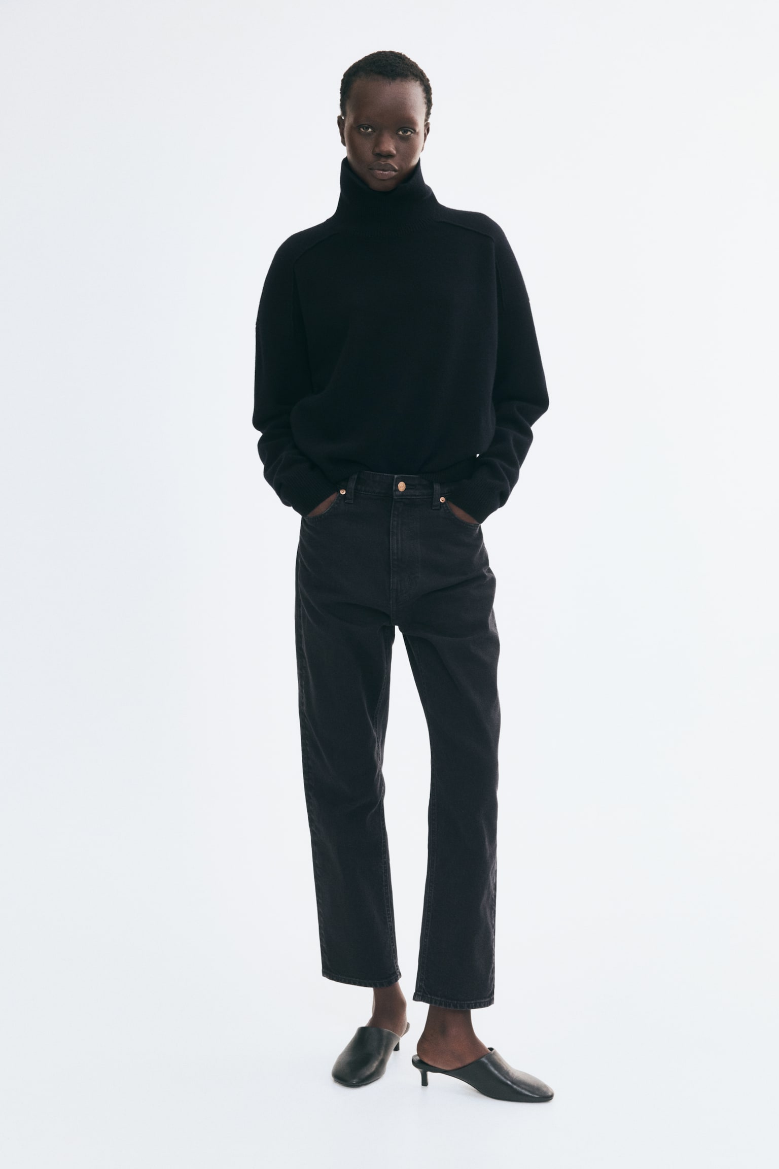Jean en denim noir à 5 poches affichant une taille haute avec une fermeture à bouton et zip à l'avant. La jambe droite se rétrécit jusqu'à un ourlet longueur cheville, et des rivets de ton cuivre accentuent les poches. - 1