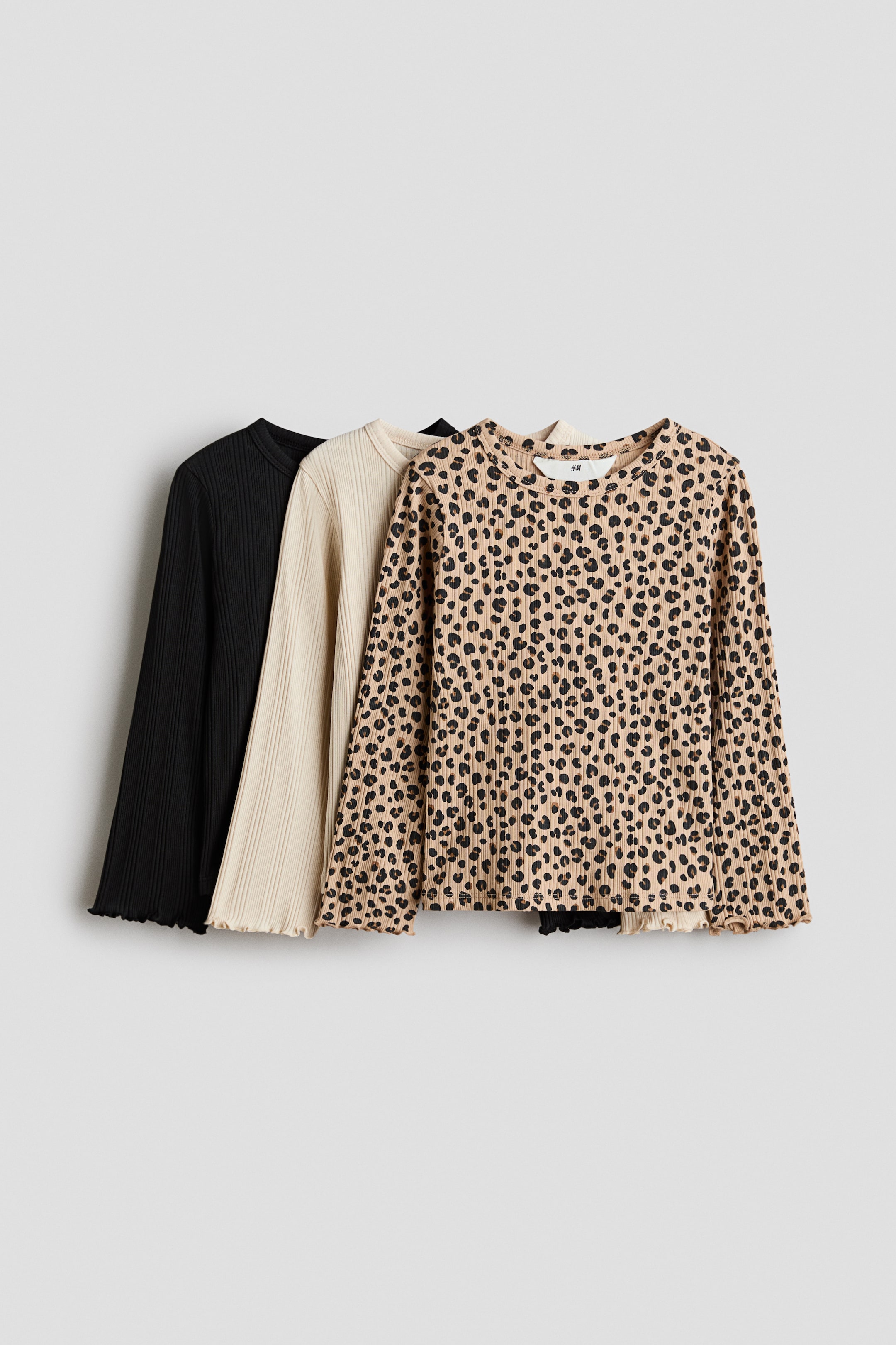 Grotere afbeelding bekijken: Drie geribbelde tops met lange mouwen worden gelaagd weergegeven vanuit een lichte voor-linkerhoek. Een zwarte top, een crèmekleurige top en een beige top met een zwart luipaardmotief zijn te zien, elk met een ronde halslijn en gegolfde zomen en manchetten.