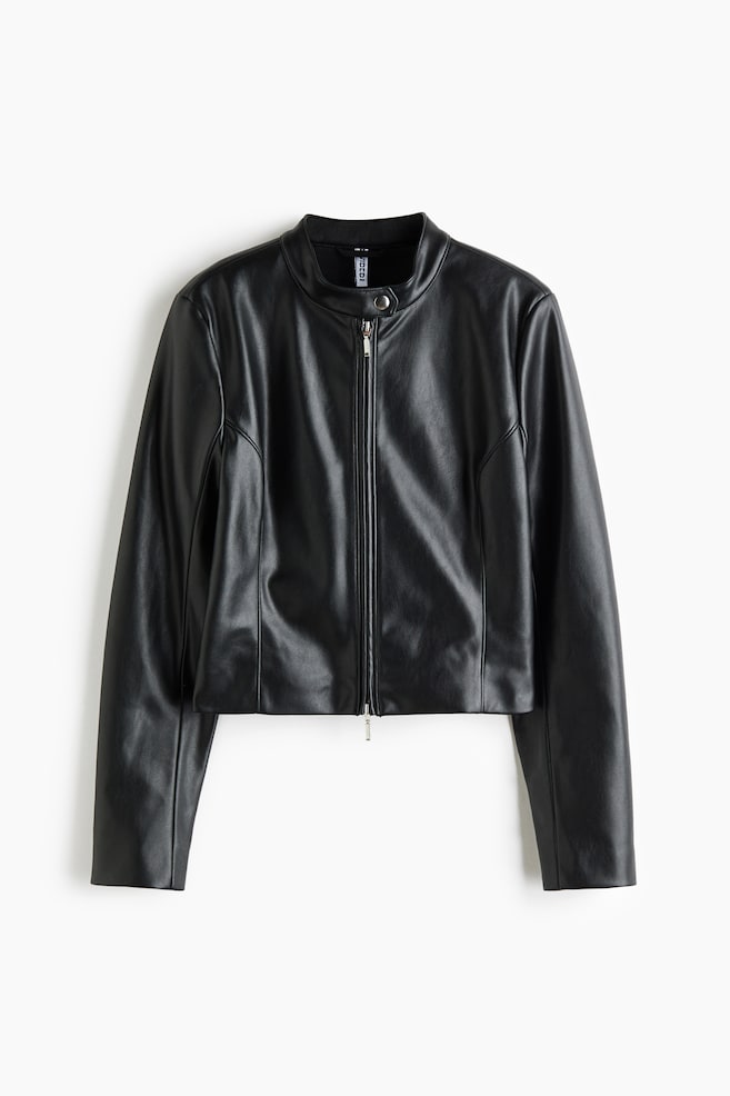 A short, fitted black faux-leather jacket is facing forwards, featuring a stand collar with a silver press stud and a two-way zip down the front. Vertical shaping seams run down the front sides to create a structured silhouette. - 1