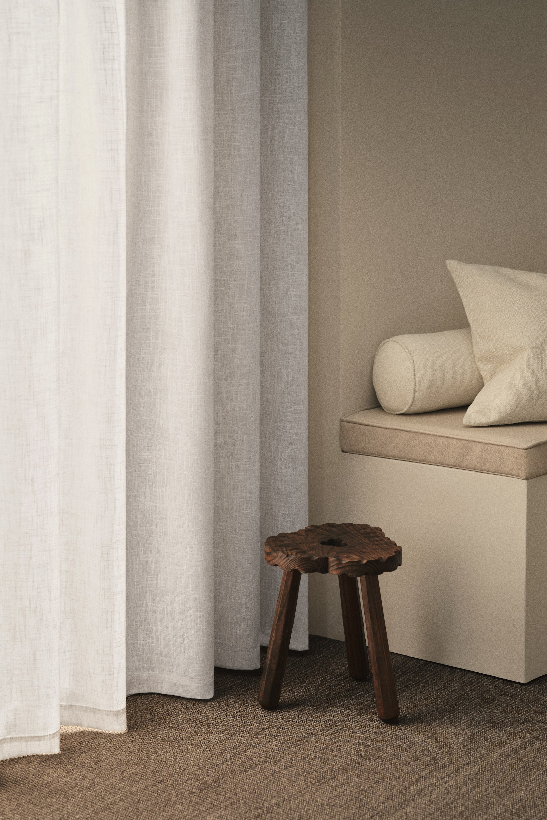 View larger image: A pair of light-colored, semi-sheer curtain panels is hanging, featuring a visible slub weave texture and forming soft vertical folds that are hemmed at the bottom.