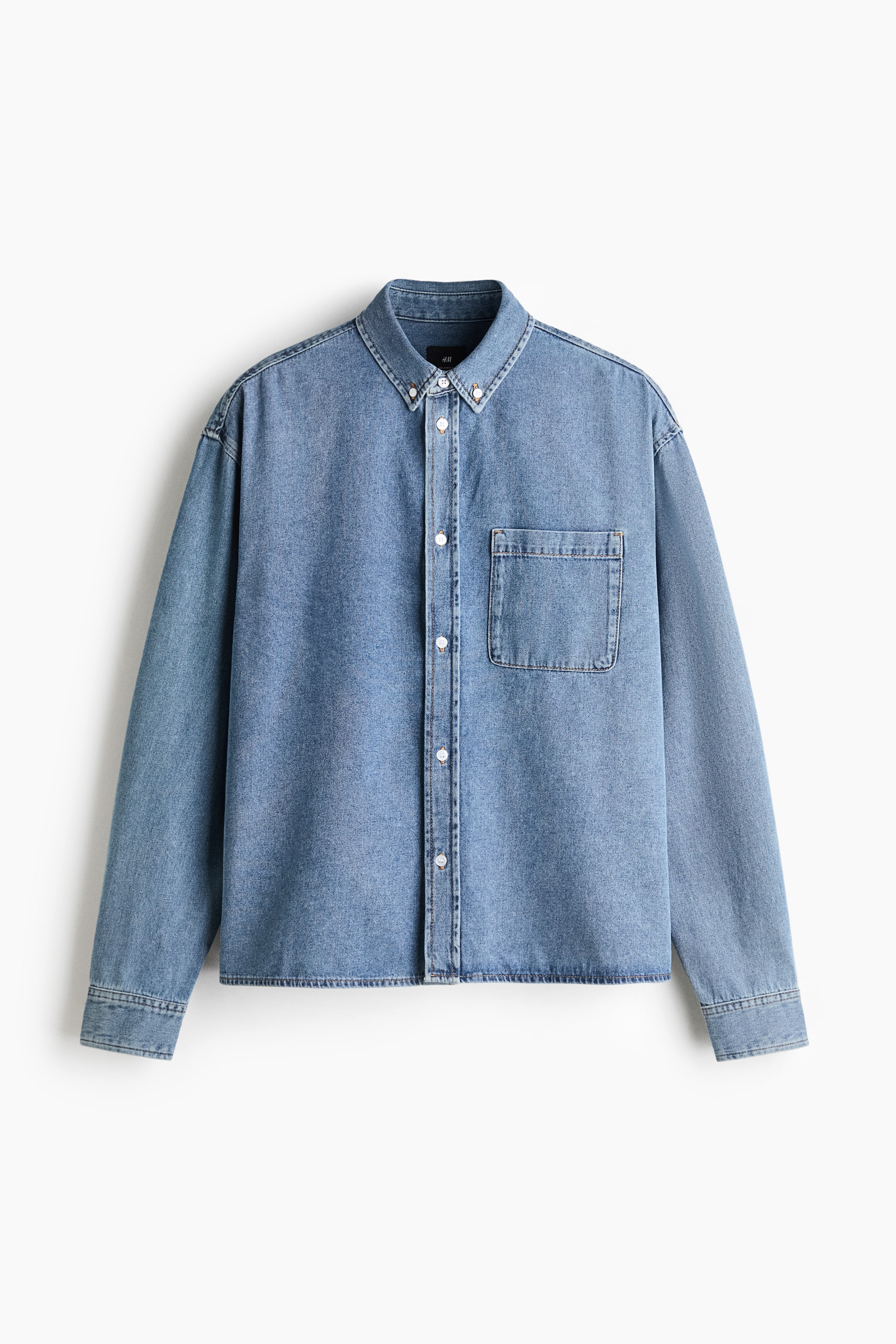 Größeres Bild ansehen: Ein hellblaues Jeanshemd ist von vorne zu sehen und verfügt über einen Button-Down-Kragen, eine durchgehende Knopfleiste mit weißen Knöpfen sowie eine aufgesetzte Brusttasche auf der linken Brustseite. Das Hemd zeigt überschnittene Schultern, lange Ärmel mit geknöpften Manschetten und einen geraden Saum.