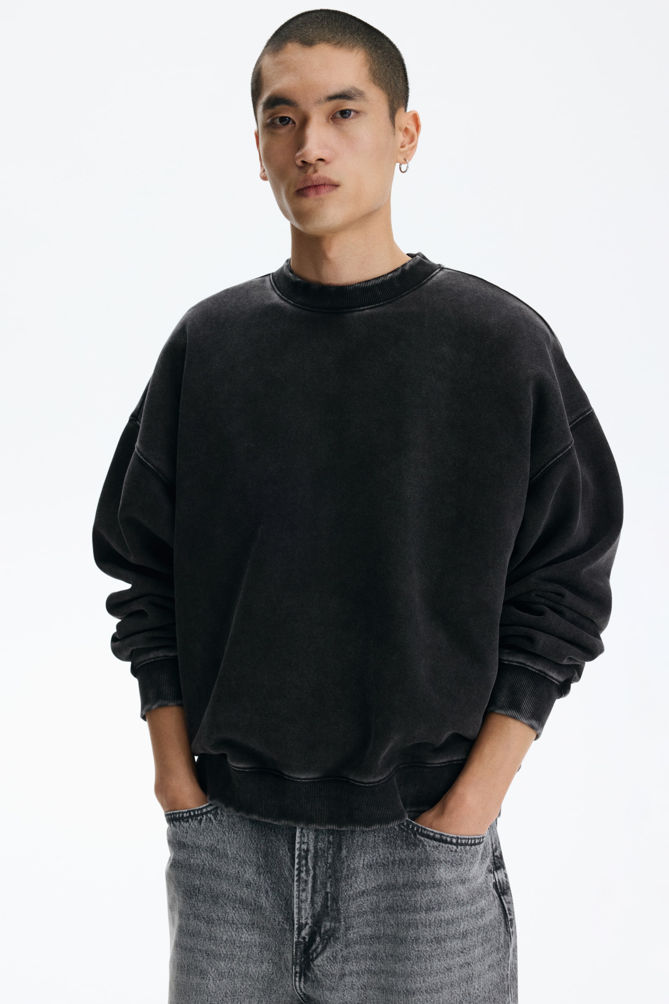 View larger image: A washed black crewneck sweatshirt is being worn, facing forward. It features an oversized fit, a ribbed collar, ribbed cuffs, and a ribbed hem.