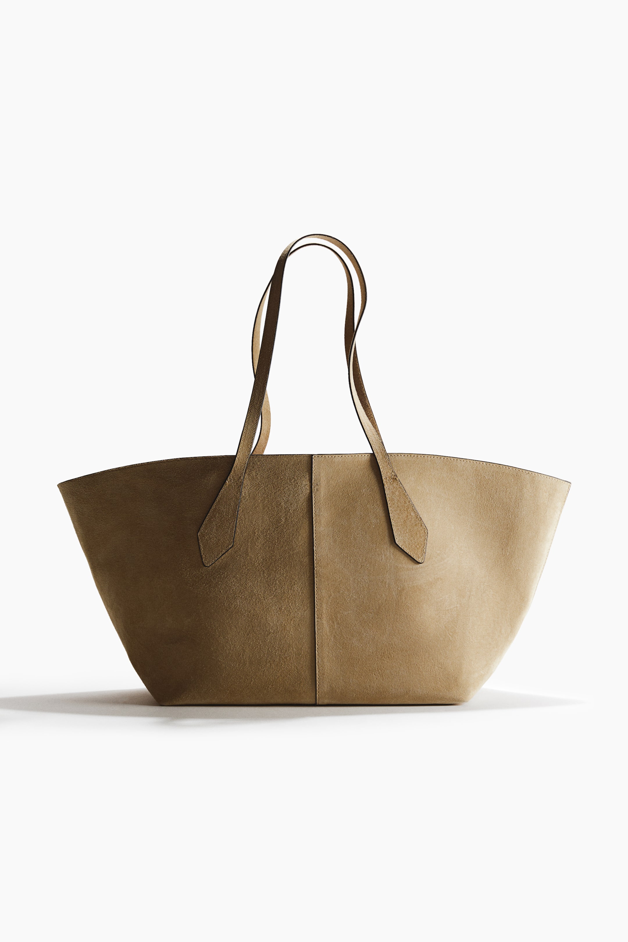 Grösseres Bild ansehen: Eine Shopper-Tasche aus weichem, hellbraunem Wildleder mit zwei langen Henkeln und einer zentralen vertikalen Naht, die das Vorderteil teilt. Die Tasche ist von vorne zu sehen, wobei der obere Rand leicht nach außen gebogen ist, da sie sich nach unten hin verbreitert.