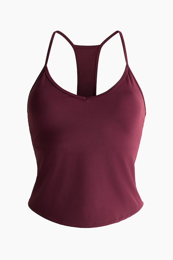 Ein bordeauxrotes Racerback-Tanktop wird von vorne gezeigt. Es verfügt über dünne Spaghettiträger, einen V-Ausschnitt und einen dezent geschwungenen Saum. - 1