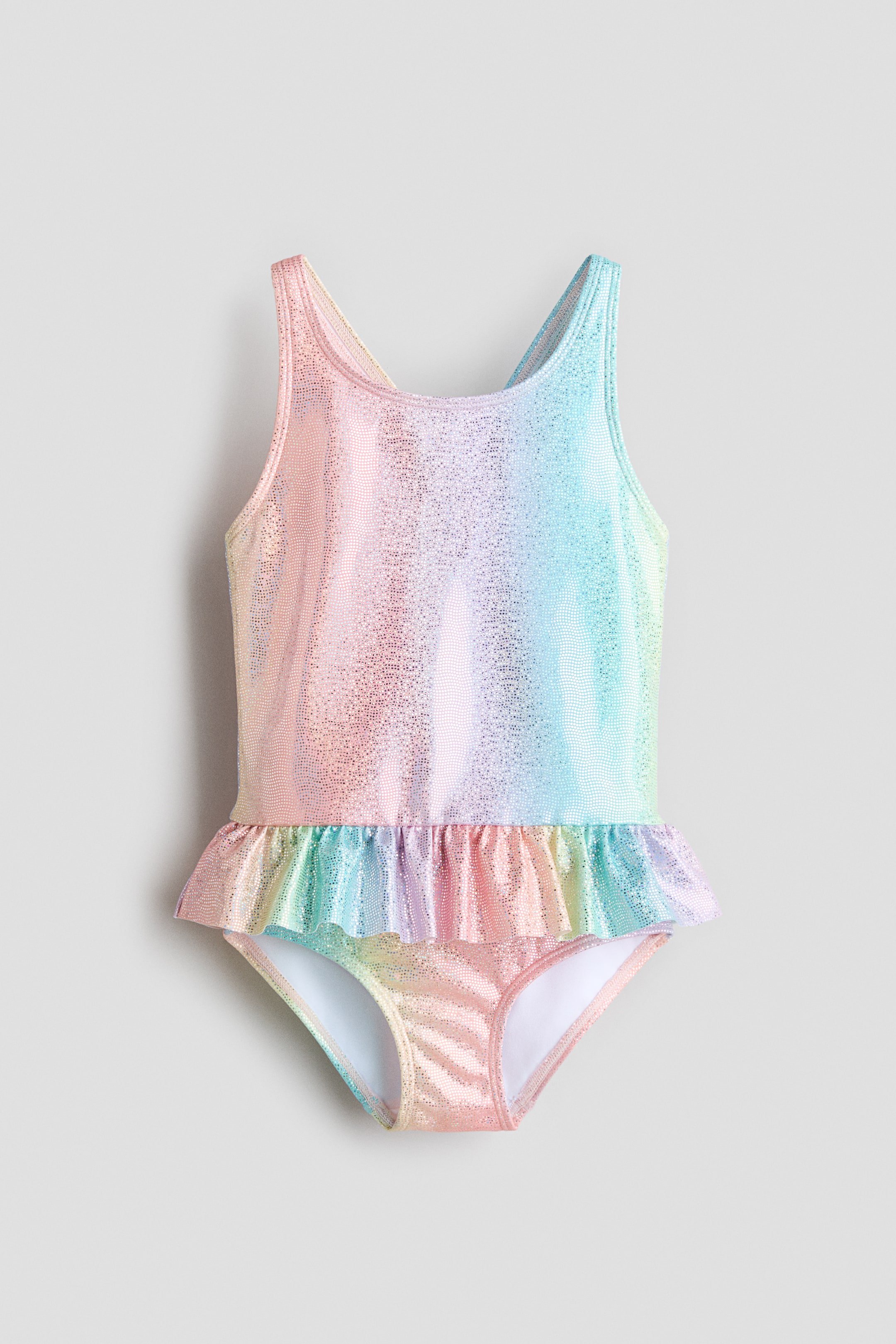 Prikaži veću sliku: Ovaj jednodelni kupaći kostim prikazan je sprijeda i odlikuje se blistavim, duginih boja gradijentnim dezenom. Dizajniran je sa bretelama u stilu potkošulje i ukrasnim volanom oko kukova.