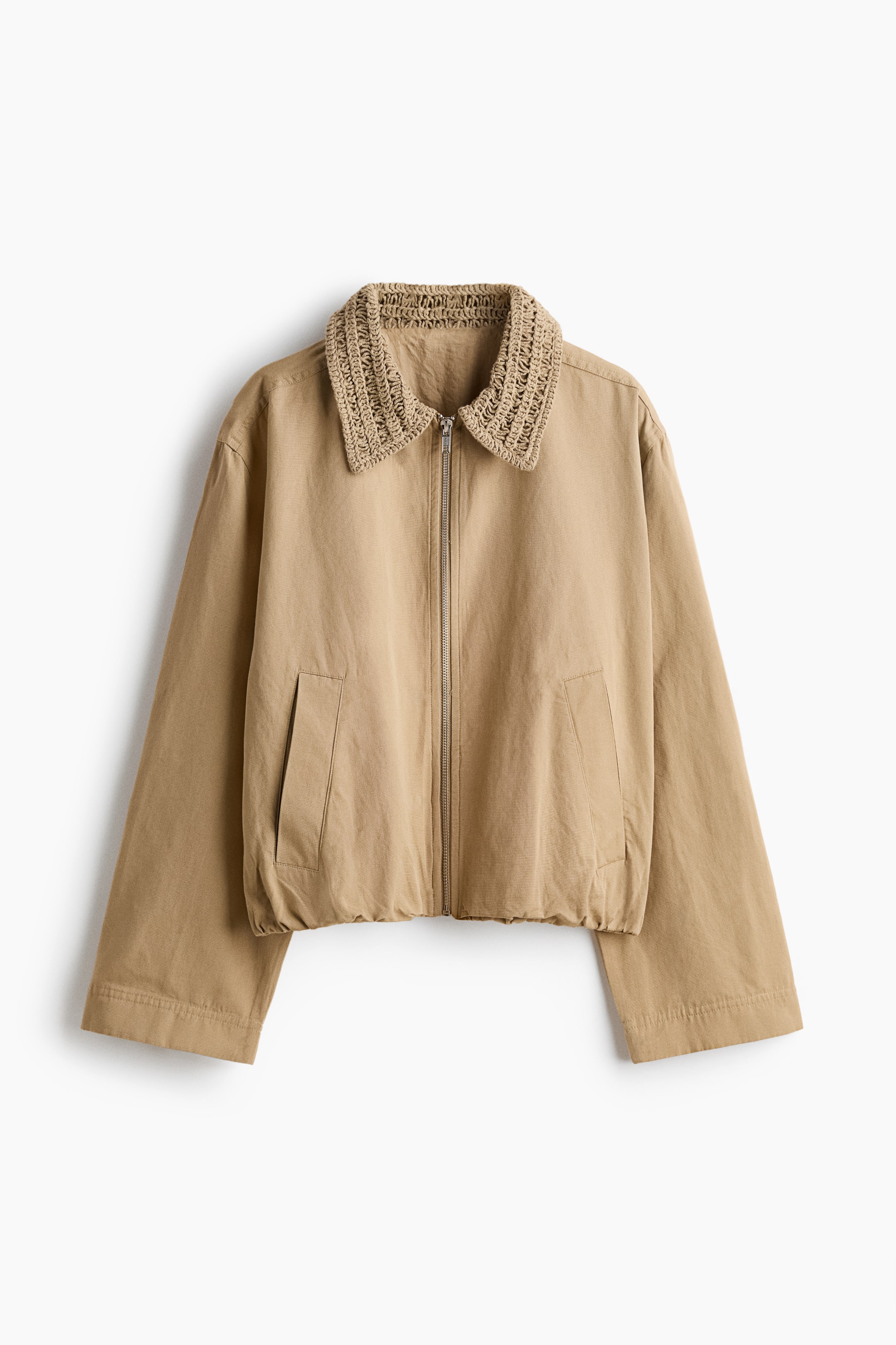 View larger image: "This tan jacket showcases a broad, structured crocheted collar along with a front zipper closure. It features two angled welt pockets at the front, and is crafted with wide, long sleeves and a gathered bottom hem."