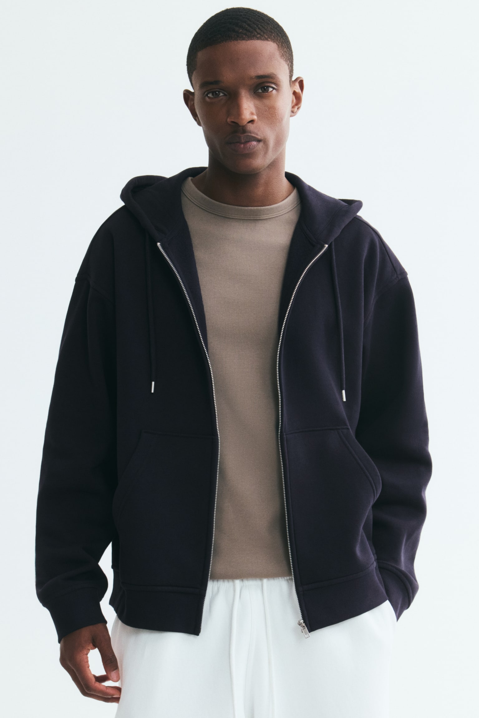 A navy zip-through hoodie is facing FRONT, featuring a hood with a drawstring, a full zip closure down the front, and a split kangaroo pocket. It has dropped shoulders, long sleeves, and ribbed cuffs and hem, presenting a loose fit. - 1