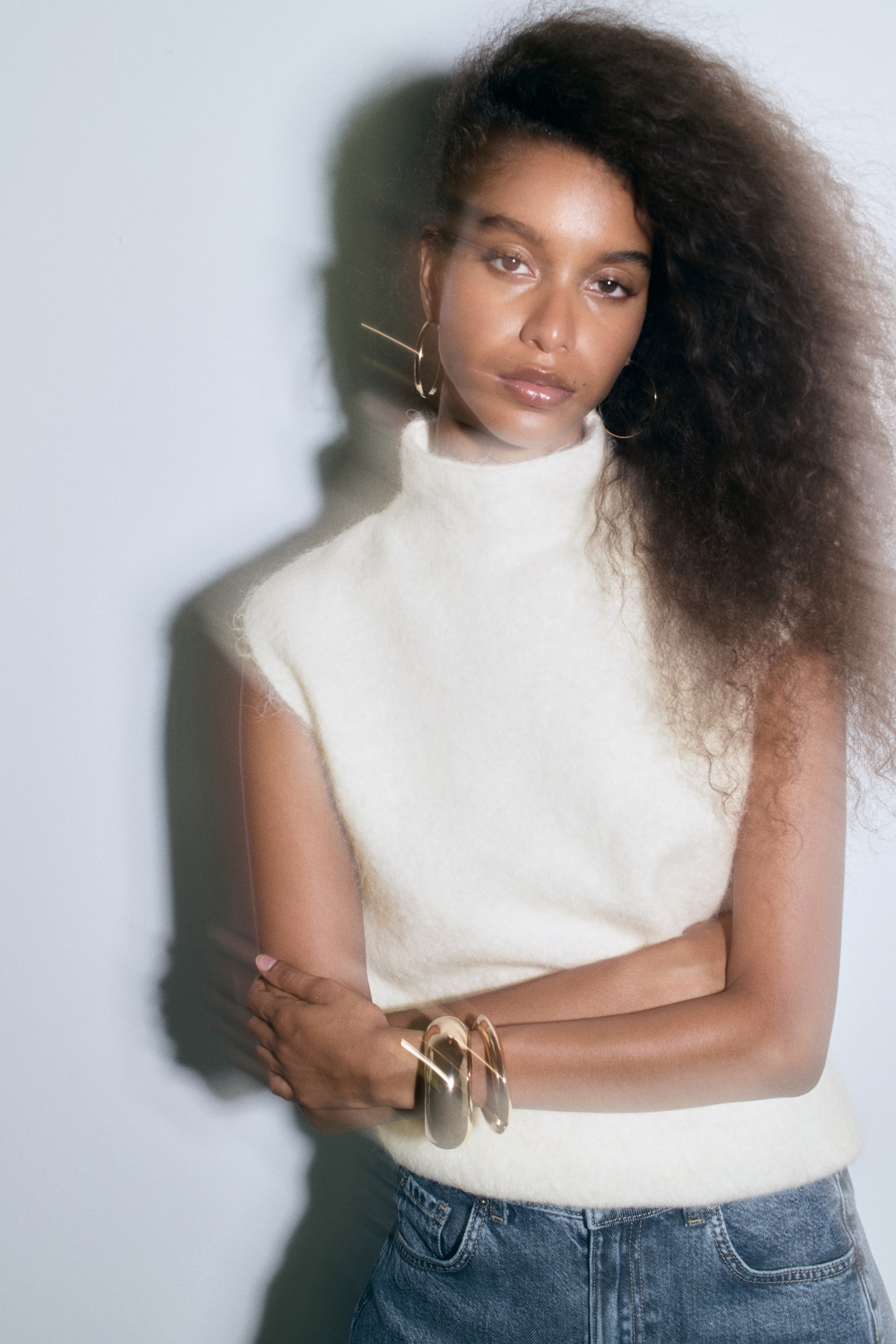 A cream-coloured sleeveless jumper featuring a fuzzy knit texture, a mock neck, and a ribbed bottom hem. - 1