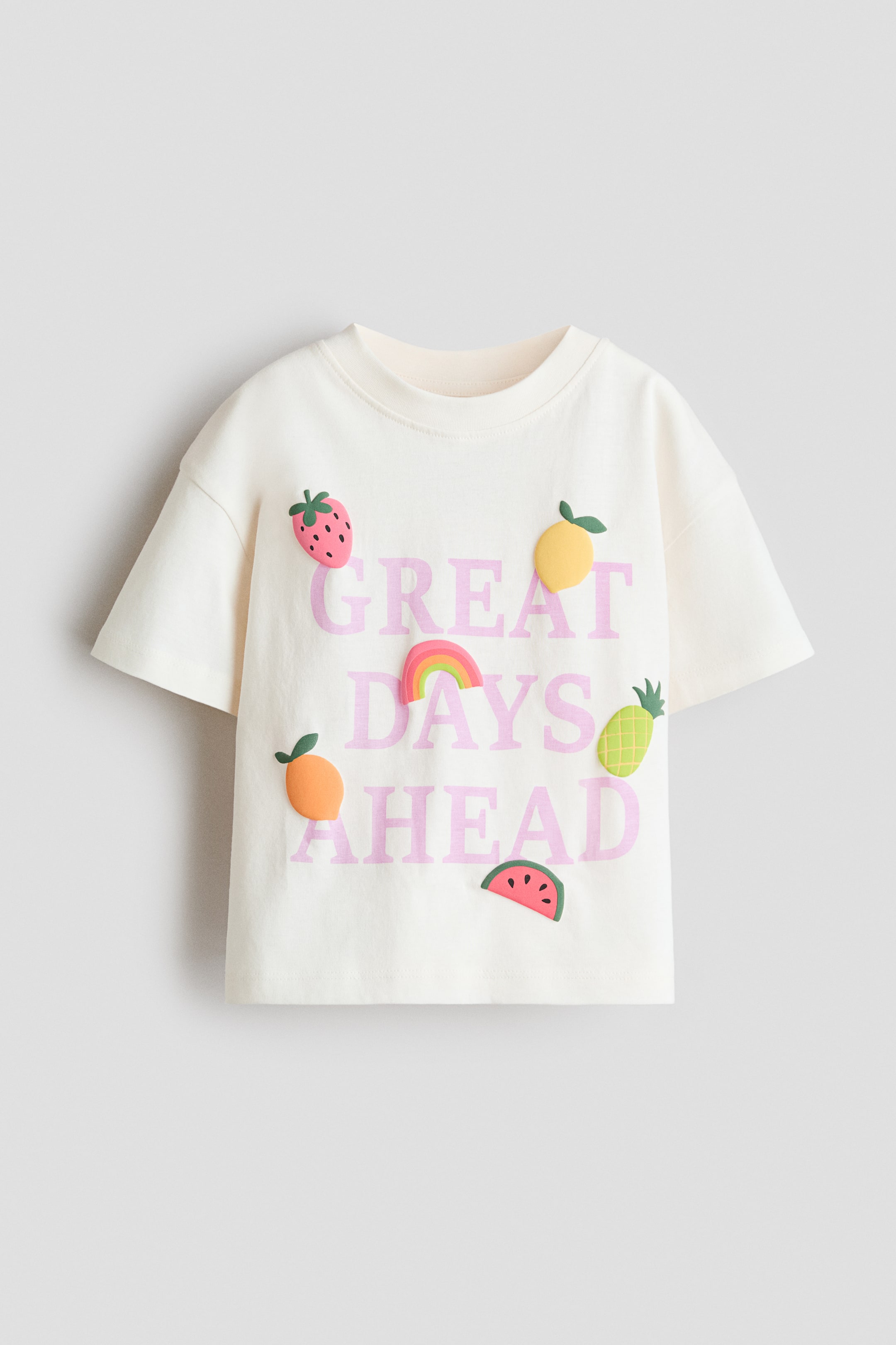 View larger image: This relaxed-fit T-shirt showcases its front, crafted from cream-coloured cotton jersey. It features a round, rib-trimmed neckline and dropped shoulders. The front is adorned with the pink phrase 'GREAT DAYS AHEAD' and colourful, raised appliqués of various fruits and a rainbow.