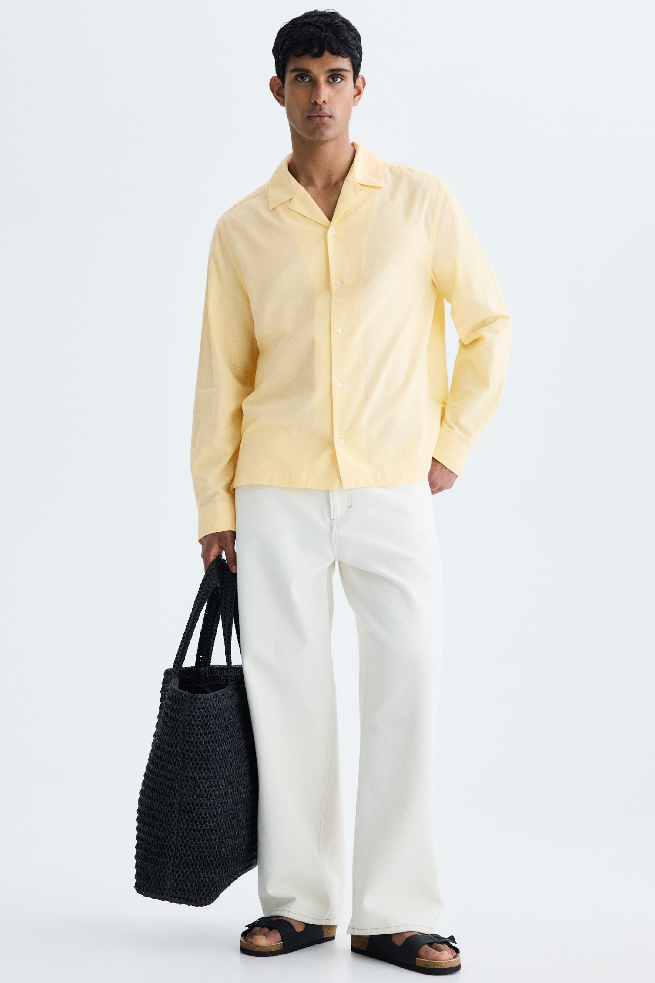 View larger image: The model is wearing a yellow long-sleeved shirt with a subtle textured weave, featuring a resort collar and light-colored buttons on the front. The shirt also has buttoned cuffs, a relaxed fit, and a straight-cut hem. One of the model's hands is casually placed in a pant pocket.