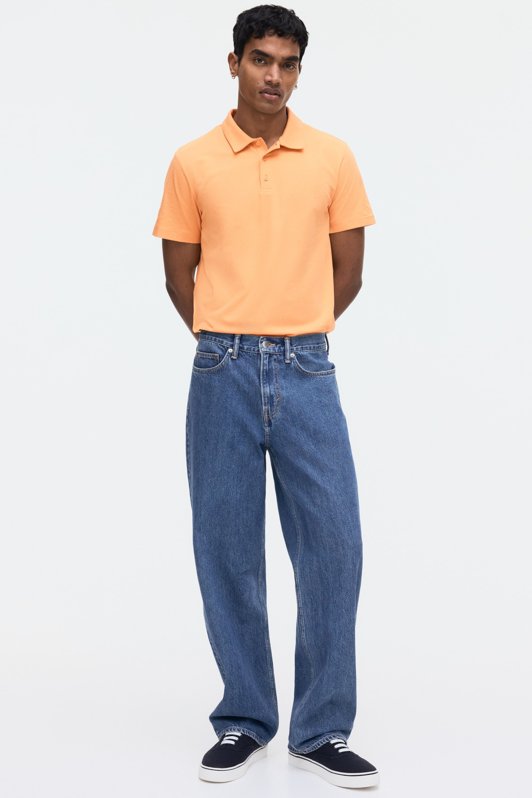 View larger image: Long blue denim jeans feature a relaxed, wide-leg silhouette and a high-rise waist, displaying a medium wash with prominent front pockets, belt loops, and a button and zipper closure.