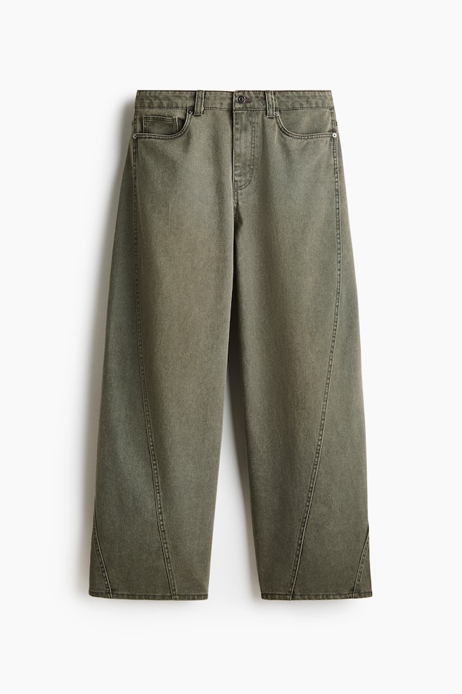 Olive green wide-leg jeans are featuring a faded wash, a button and zipper closure, and front scoop pockets. Prominent curved vertical seams are running down the front of each leg, ending in a notched hem. - 1