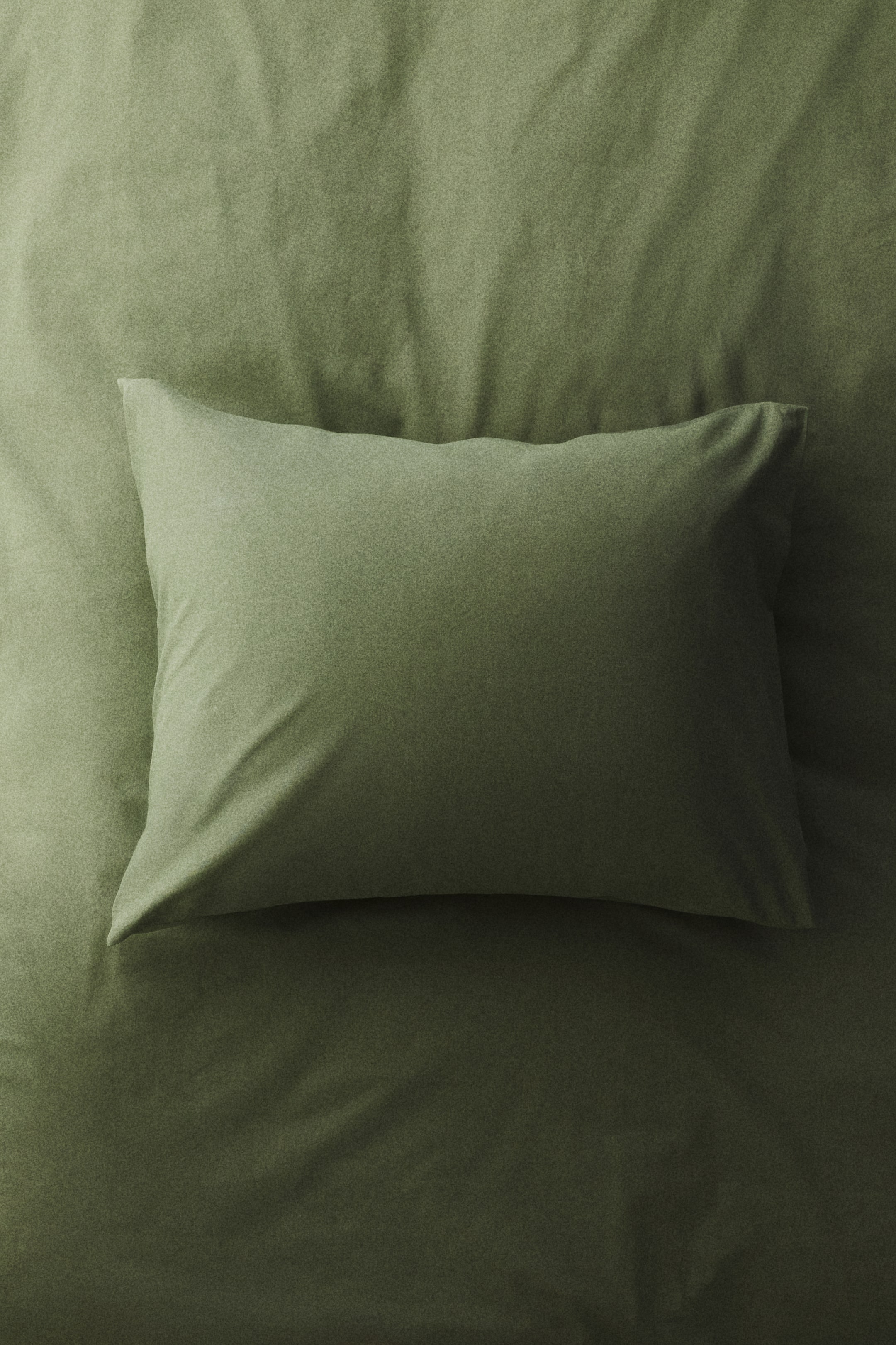 View larger image: An olive green pillowcase, crafted from a fine-threaded cotton weave, is lying flat, viewed from the front. It features an envelope opening.