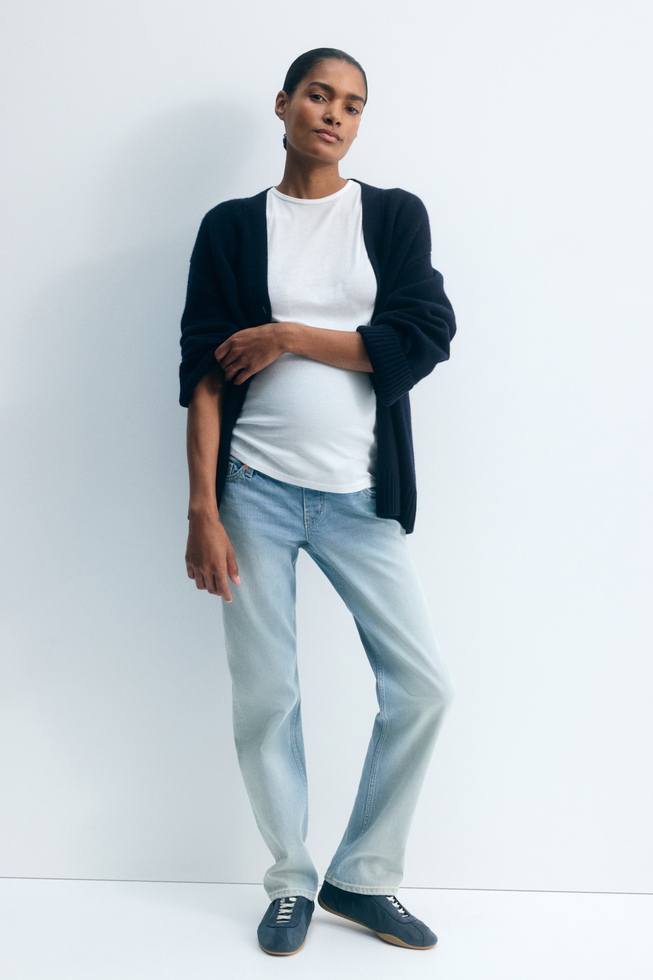 Visa större bild: Ljusvättade mammabyxor i denim med rak benvidd bärs av modellen, tillsammans med en vit t-shirt och en öppen marinblå cardigan. Jeansen har en regular fit över låren och en rak skärning ner mot bensluten, och vilar ovanpå mörkblå sneakers.