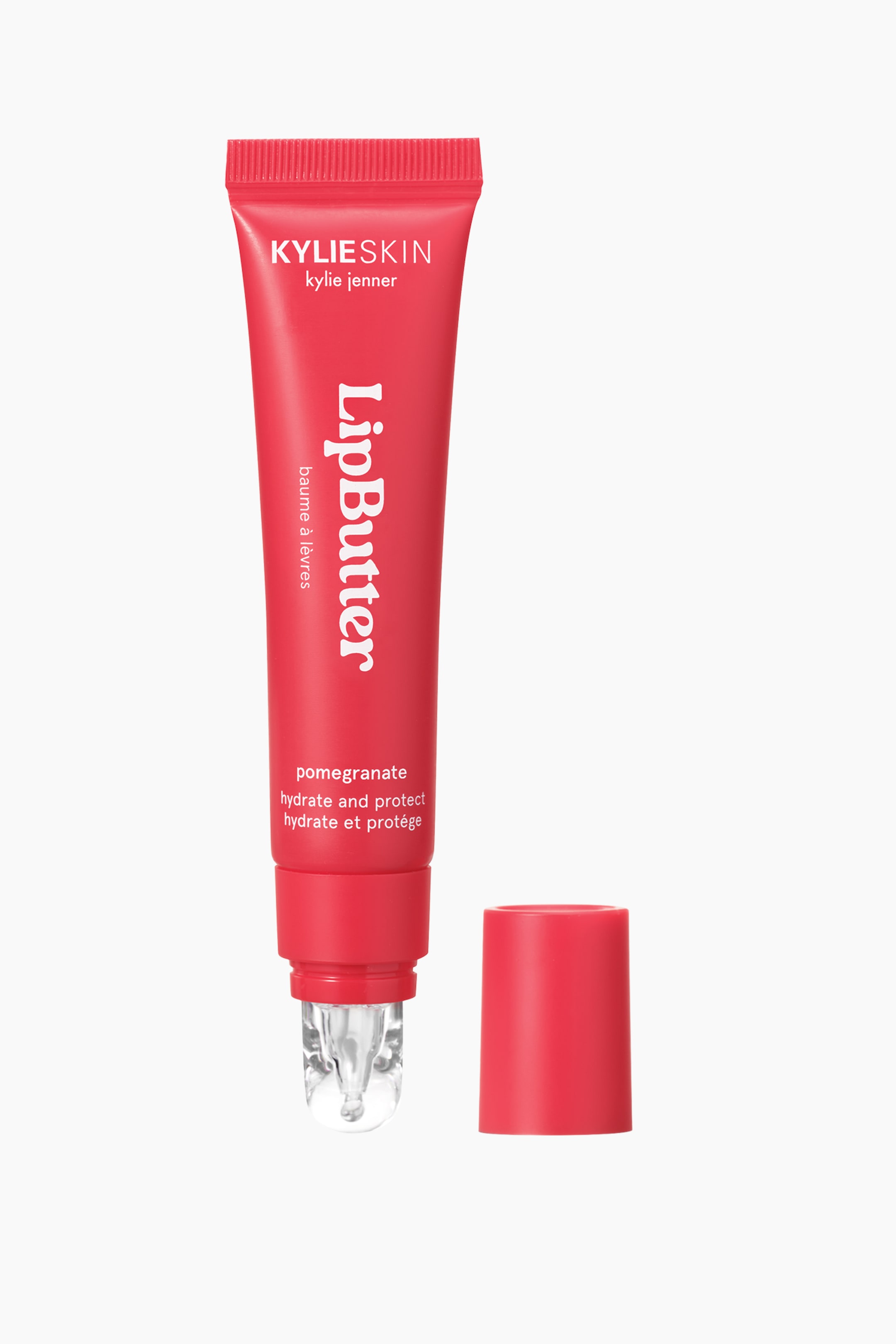 Visa större bild: Ett rött Kylie Skin Lip Butter-rör står upprätt, något framåtlutat, och visar vit varumärkes- och produktinformation. En genomskinlig rollerball-applikator sträcker sig från botten, och dess matchande röda lock ligger avtaget till höger.