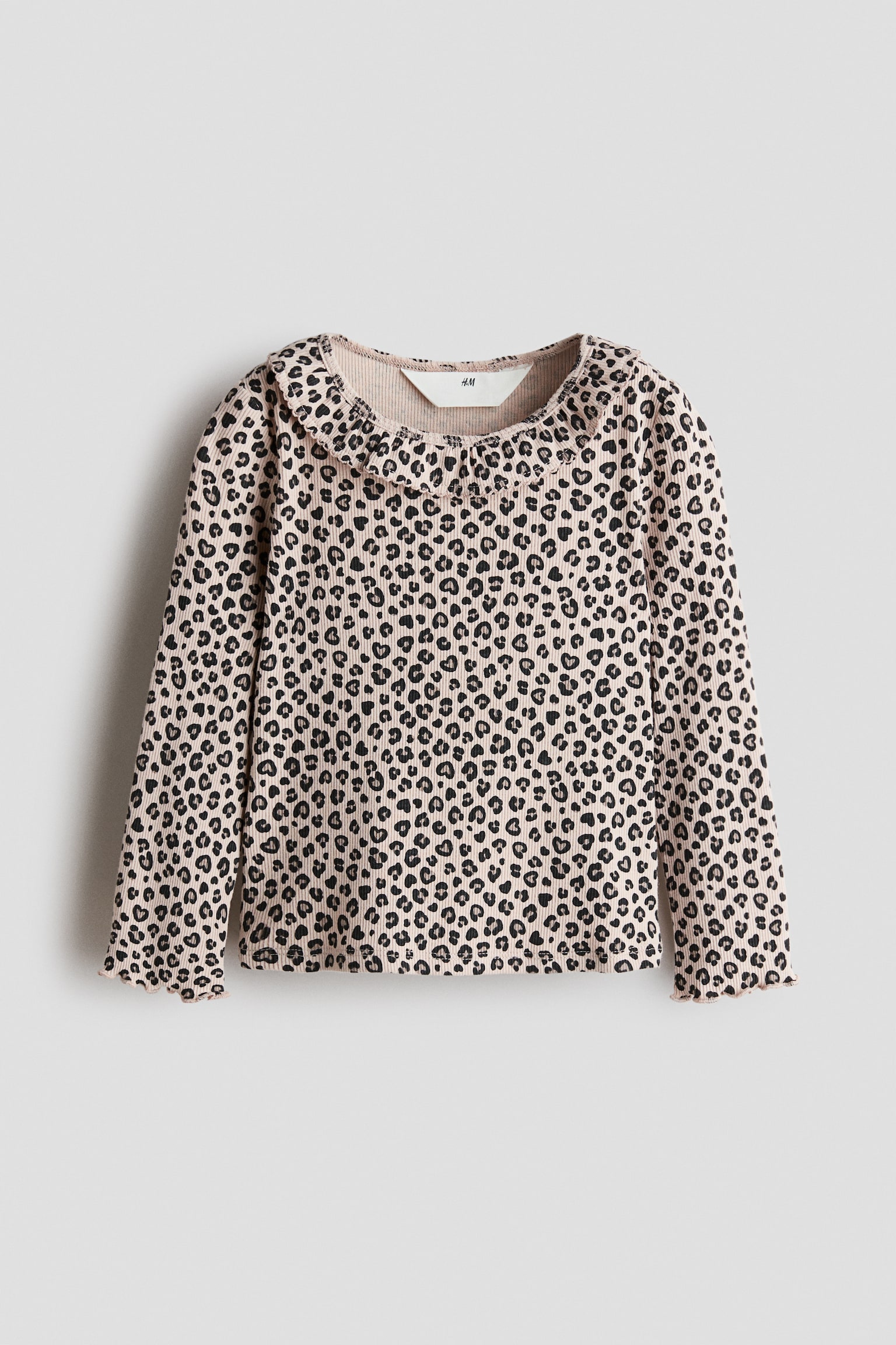 A long-sleeved ribbed top is shown from the front, featuring an all-over black leopard print on light pink fabric. The top has a ruffled collar and lettuce-edge hems at the cuffs.