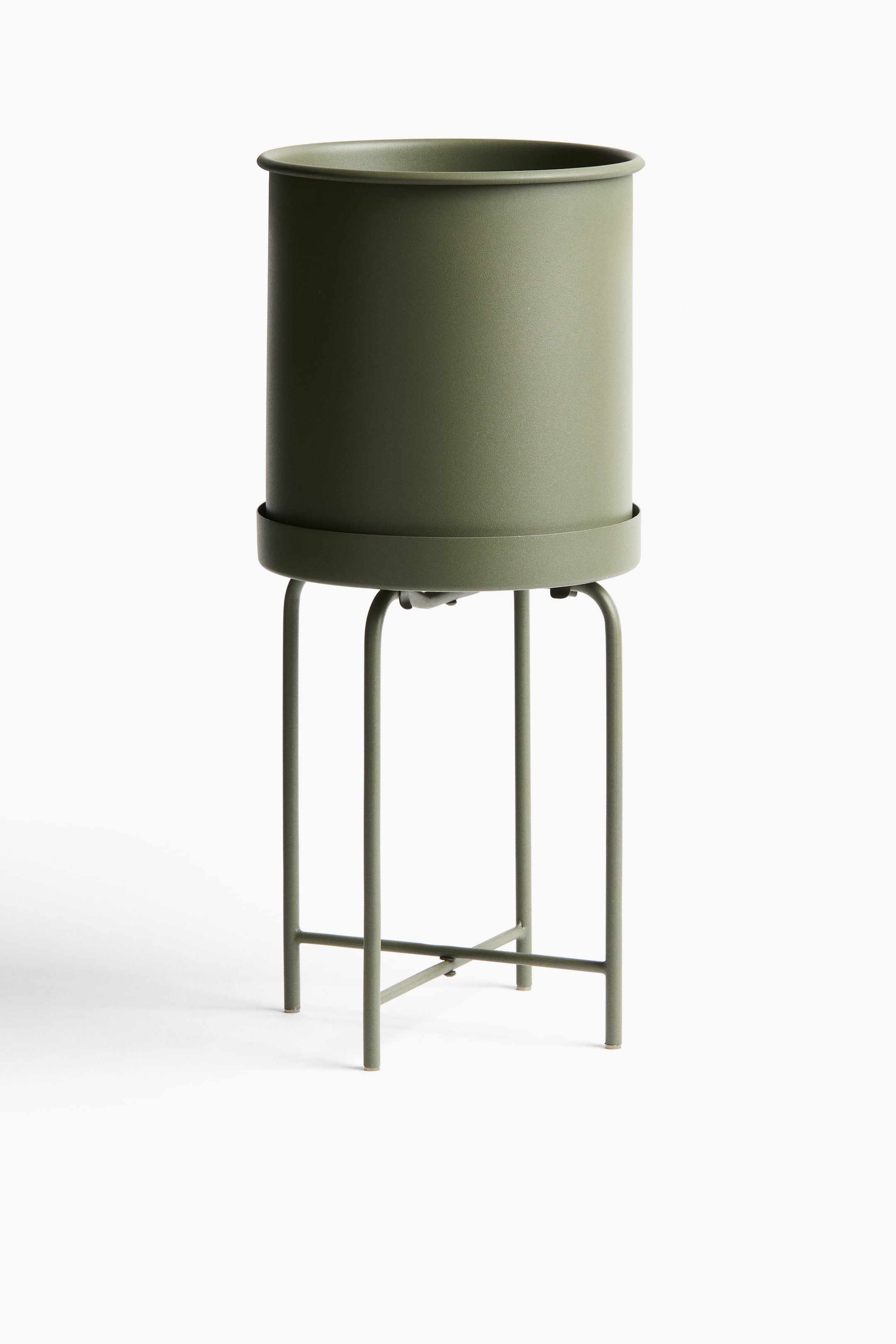 View larger image: "A front view showcases an olive green metal plant pot and stand. The cylindrical pot sits on a matching saucer, supported by a tall, four-legged metal stand with a cross-brace near its base."