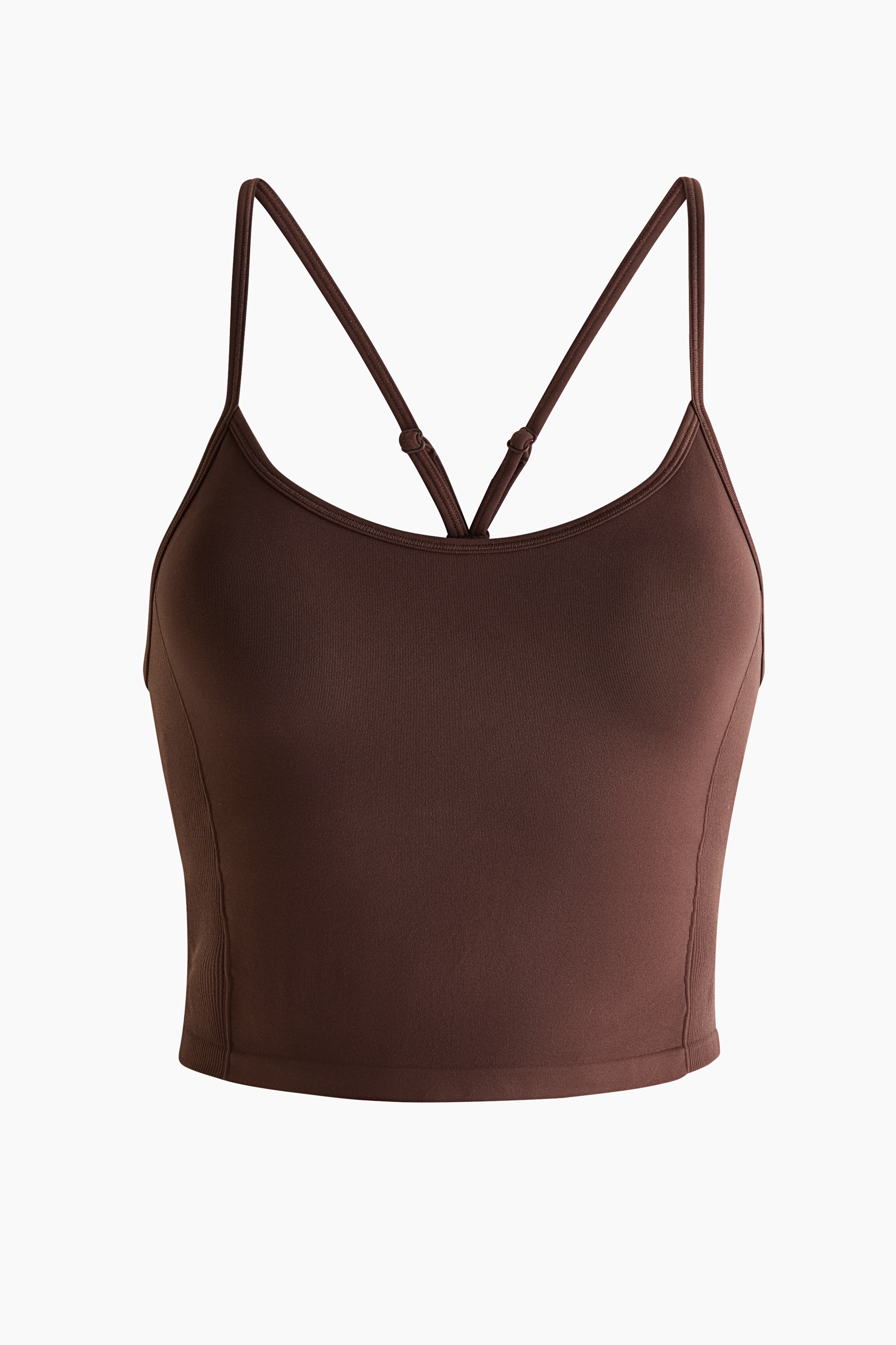 A dark brown athletic set is presented, featuring a crop top with thin shoulder straps, a smooth front panel, ribbed side panels and a ribbed hem. The matching high-waisted leggings feature a wide, folded-over waistband held open by hands, and a smooth, form-fitting silhouette.