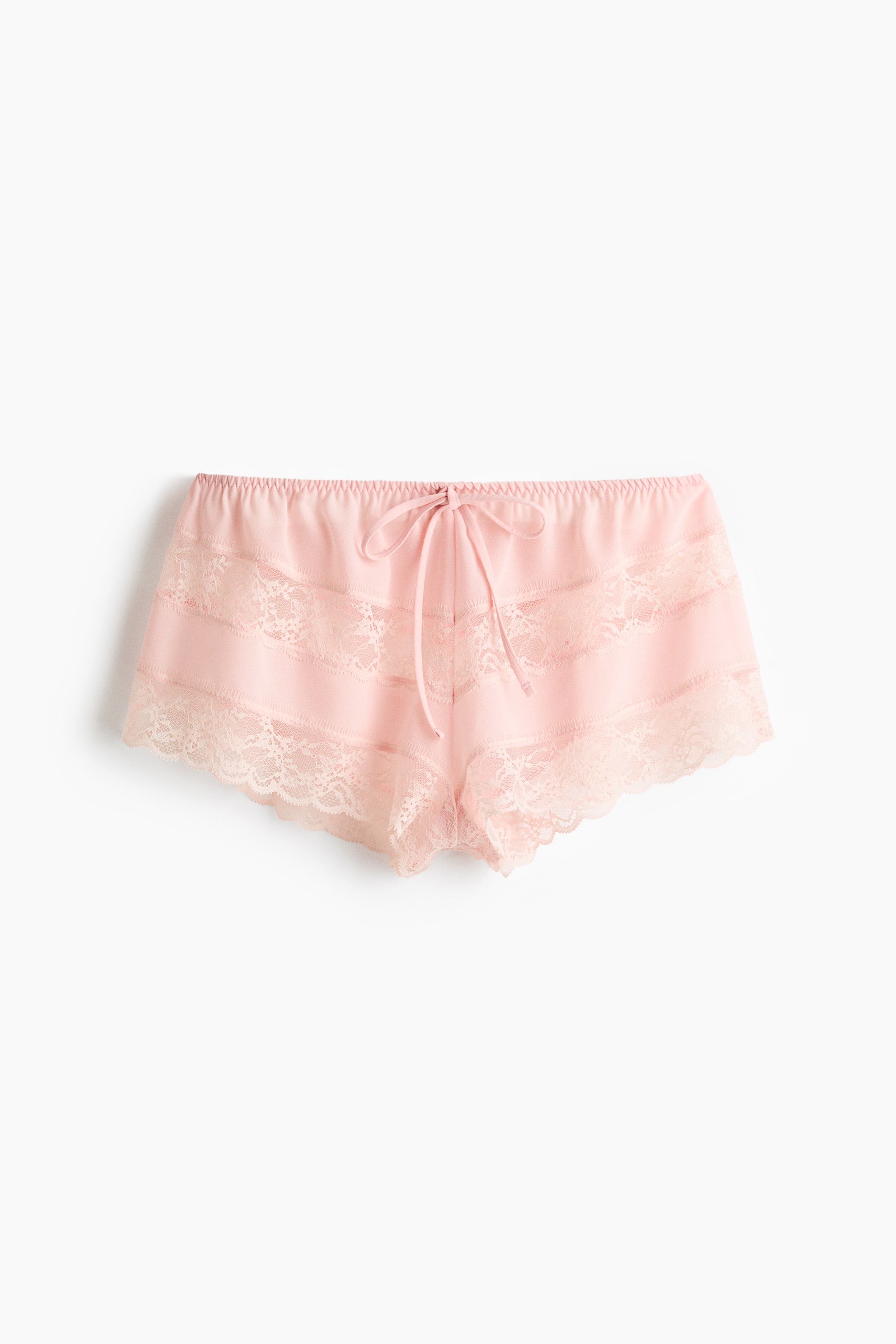 Visa större bild: Framåtvända rosa chiffongtrosor med hög, elastisk midja och smala knytband knutna i mitten. Spetsdetaljer pryder de lågt skurna benöppningarna och går horisontellt över framsidan.