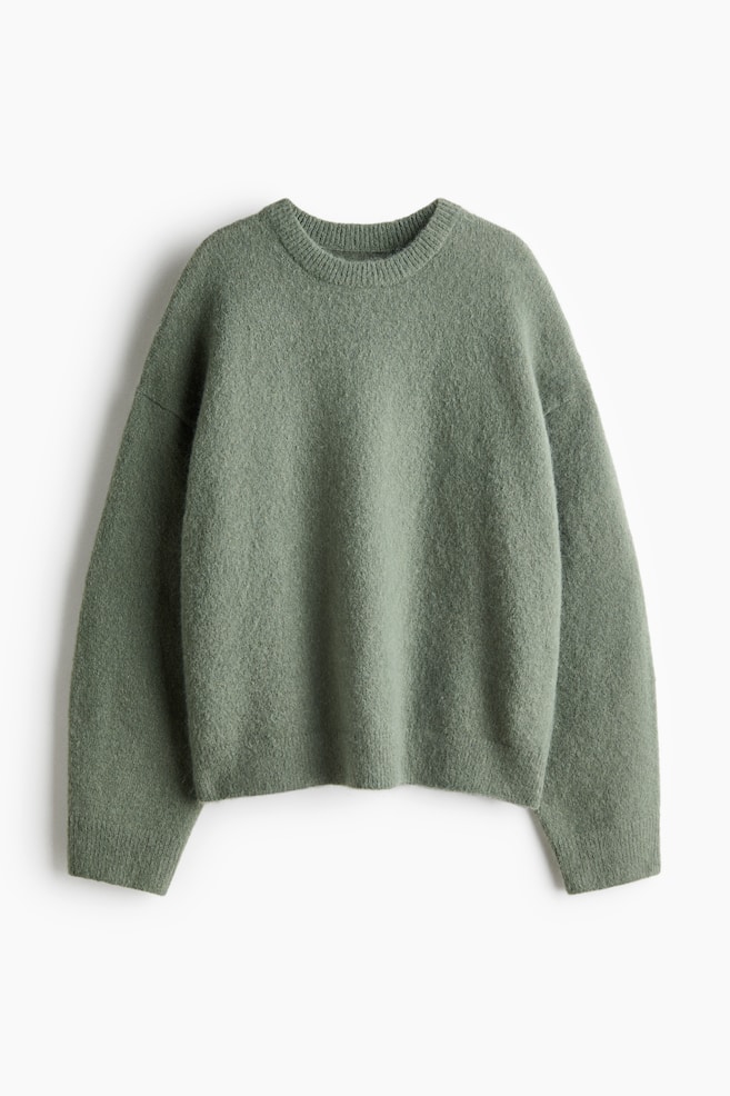 Un pull en maille vert sauge est prÃ©sentÃ© de face, mettant en valeur un col rond cÃ´telÃ©, des Ã©paules tombantes et des manches longues. Le pull prÃ©sente des dÃ©tails cÃ´telÃ©s aux poignets et Ã  lâourlet, avec une finition douce et texturÃ©e. - 1