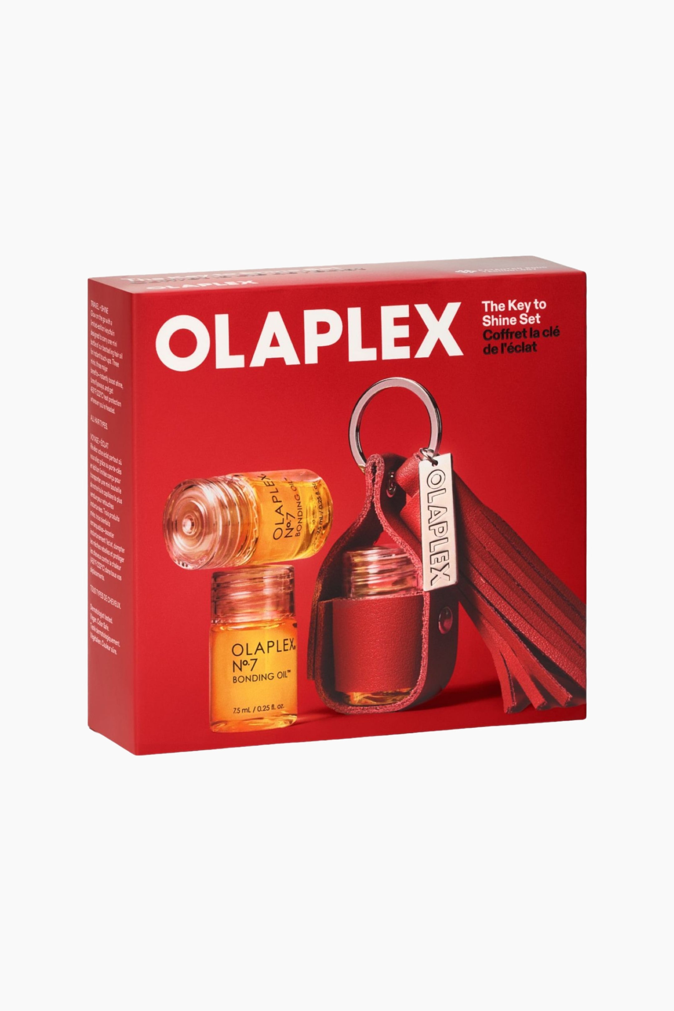 Vis større bilde: The Key To Shine Set vises i en rød, rektangulær boks i trekvart vinkel, med den tydelige hvite Olaplex-logoen på forsiden. Emballasjen viser bilder av to små flasker med Olaplex No. 7 Bonding Oil og en rød nøkkelholder i lær, detaljert med en sølvfarget nøkkelring, merkeetikett og dusk.