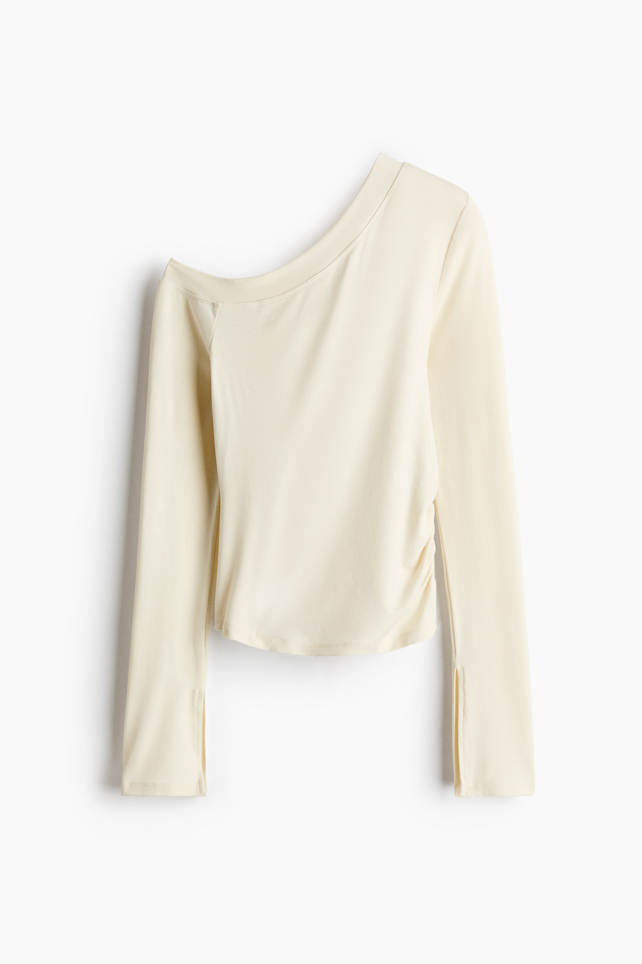 View larger image: A light cream one-shoulder top is shown from the front, featuring an asymmetric neckline with one shoulder exposed and long sleeves with slits at the cuffs. A gathered seam creates a ruched effect on one side of the waist, and the hemline is gently curved.