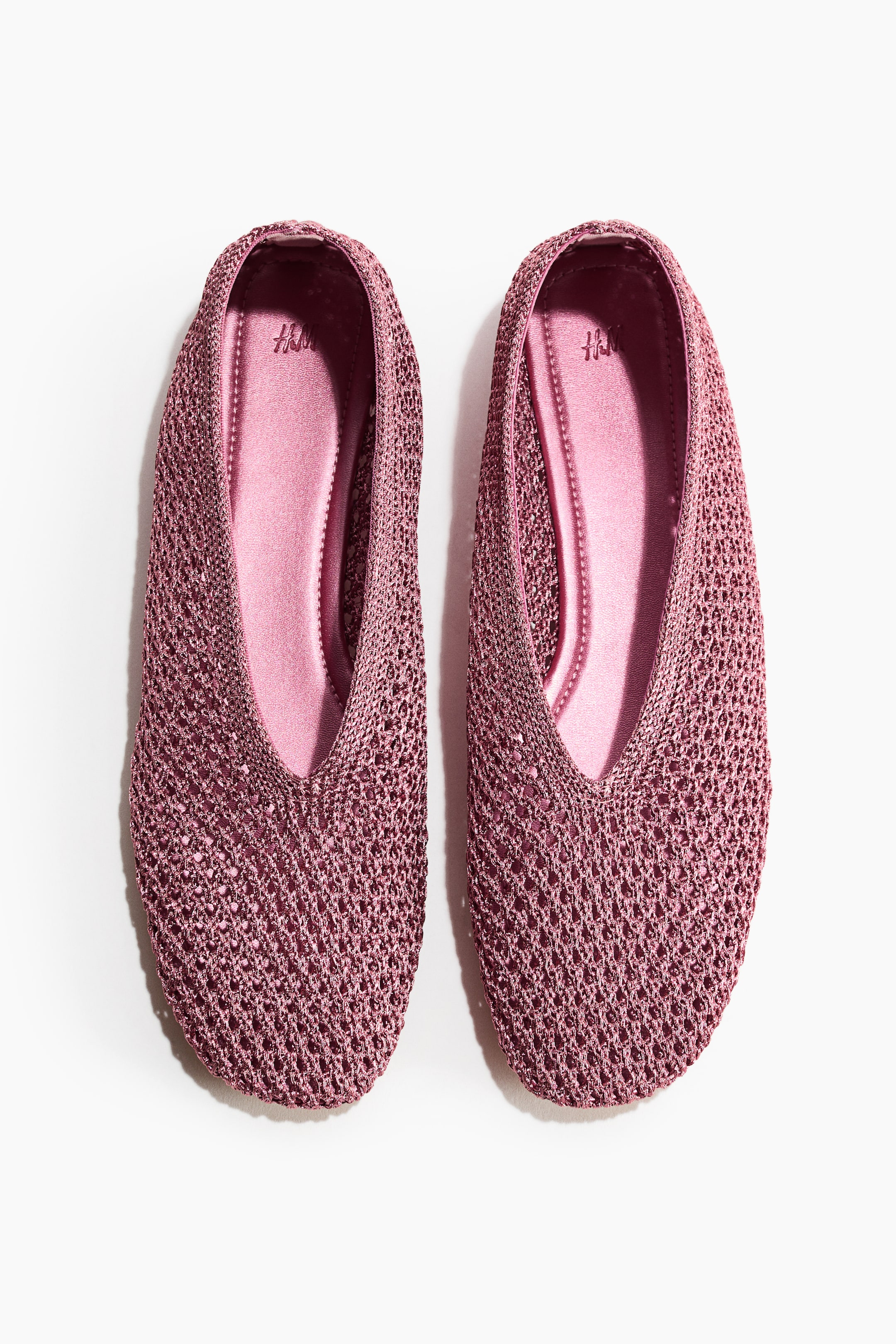 View larger image: Introducing a chic pair of mauve ballet flats, showcased from the front. These flats boast intricately braided plastic straw uppers and elegantly rounded toes. The V-shaped cut reveals glossy mauve insoles, adding a touch of sophistication.