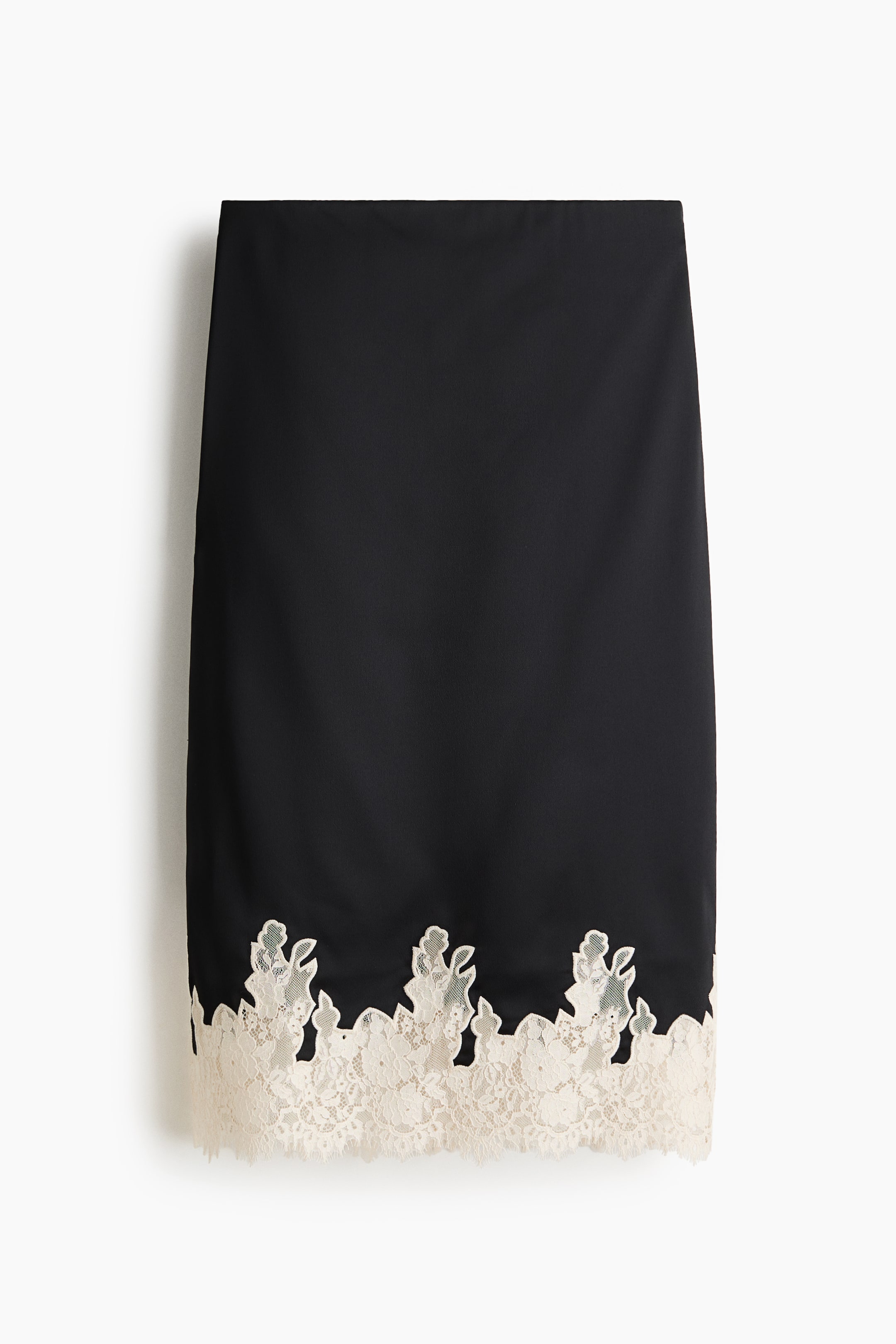 View larger image: A black pencil skirt is showcasing its front, featuring a broad, off-white lace trim with a floral and leaf motif along its scalloped bottom edge.
