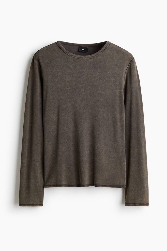 A long-sleeved shirt is presented from the front, featuring a dark, faded olive green ribbed knit fabric. It is designed with a crew neck, long sleeves with finished cuffs, and an exposed raw-edge hem at the bottom. - 1