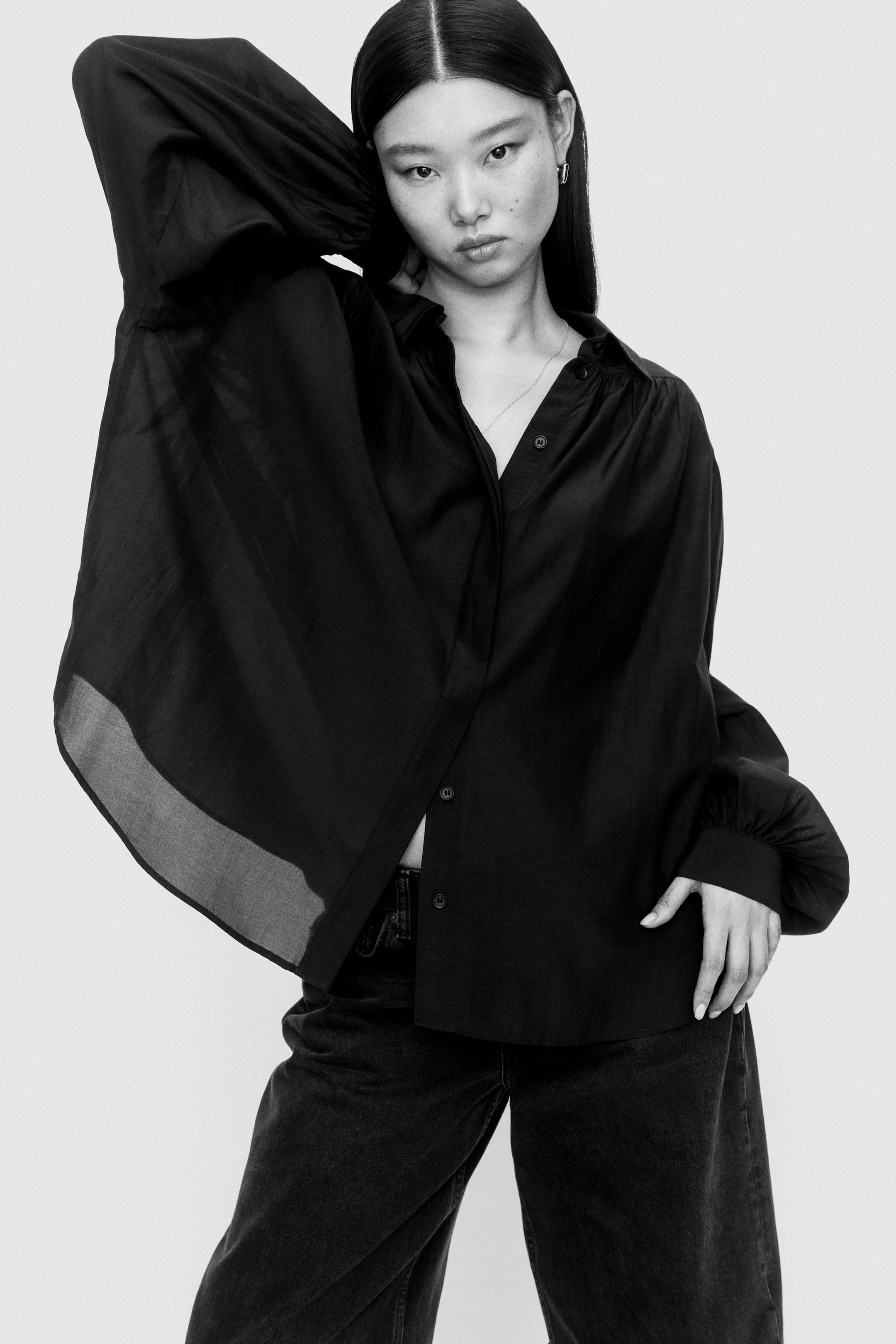 View larger image: The black shirt showcases a classic collar and a button-front closure, styled with a partially unbuttoned look. It features voluminous long balloon sleeves that culminate in fitted cuffs and drapes in a loose, flowing fit crafted from lightweight fabric, with the front facing the viewer.