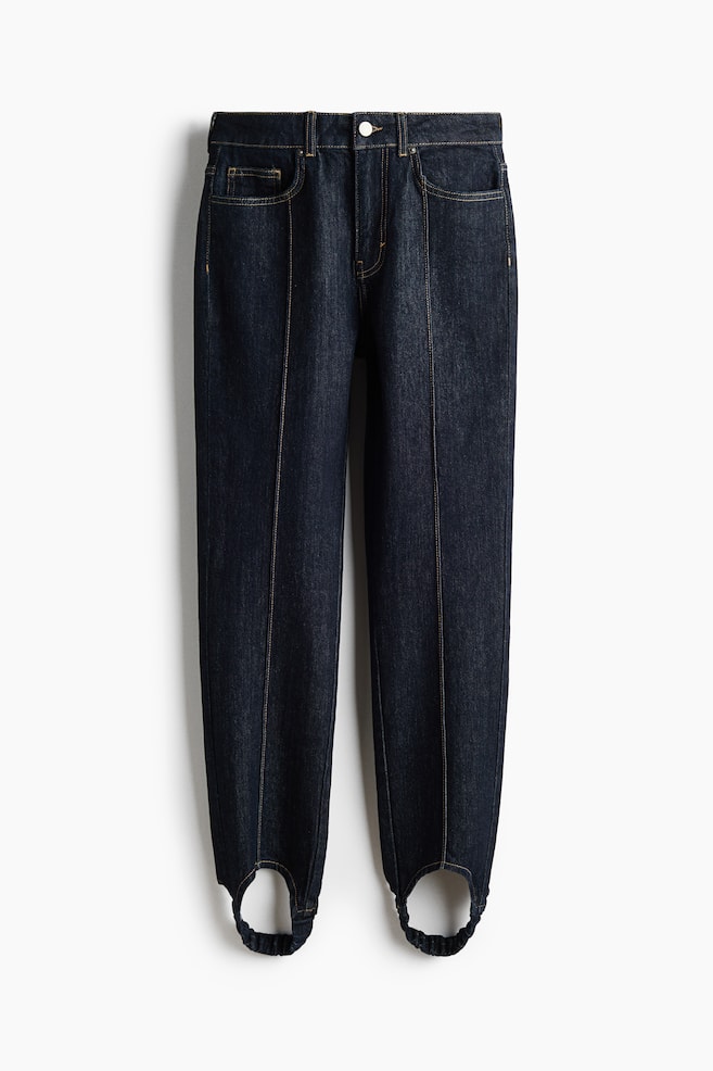 Se muestra un par de vaqueros pitillo tipo estribo en denim azul de lavado oscuro, vistos de frente, con diseÃ±o de cintura alta y cinco bolsillos, y pespuntes en contraste. Las costuras de pinzas verticales recorren el centro de cada pernera, que se estrechan hasta unas tiras de estribo elÃ¡sticas en los puÃ±os. - 1